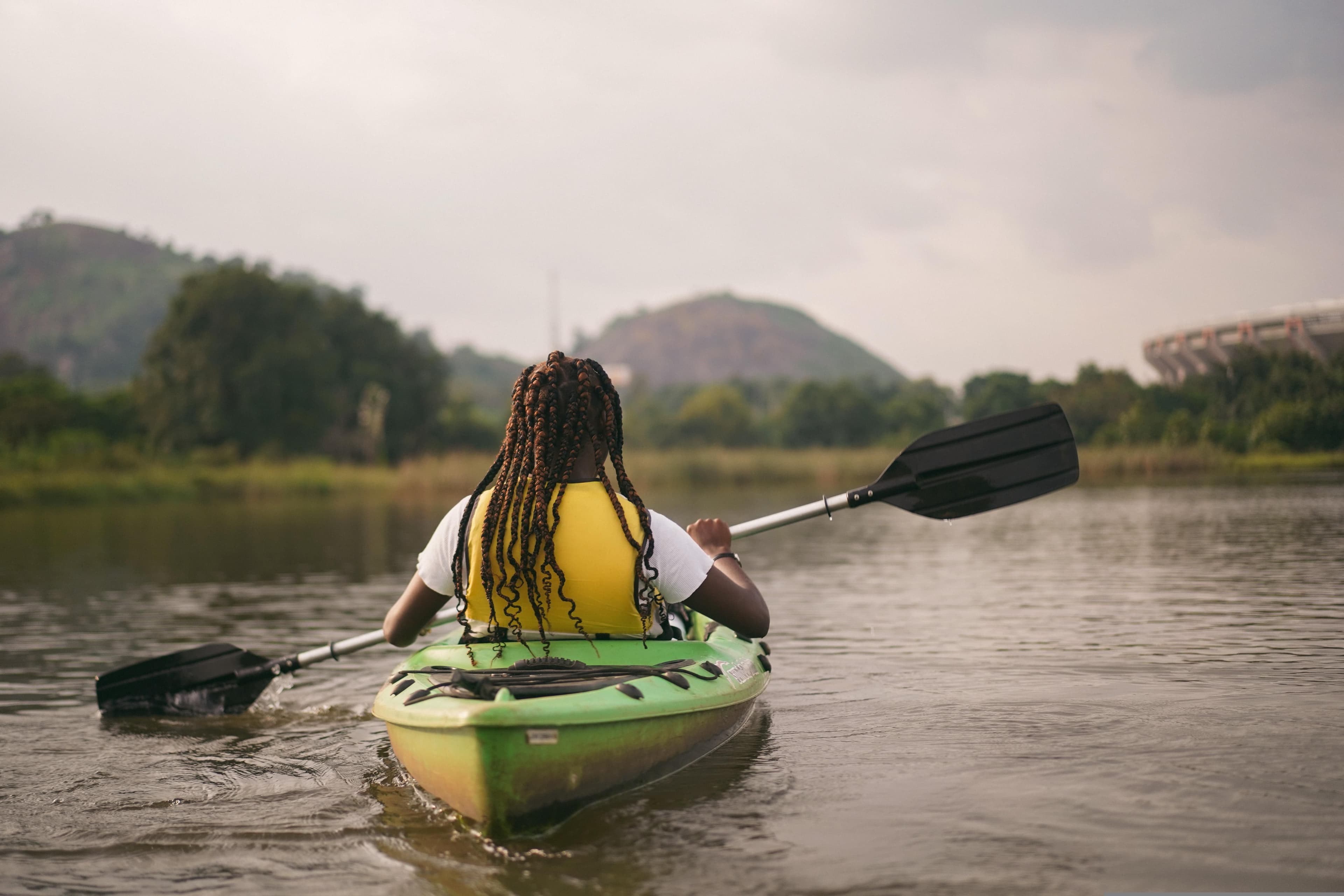 Back of a girl in a kayak on a river in Laos