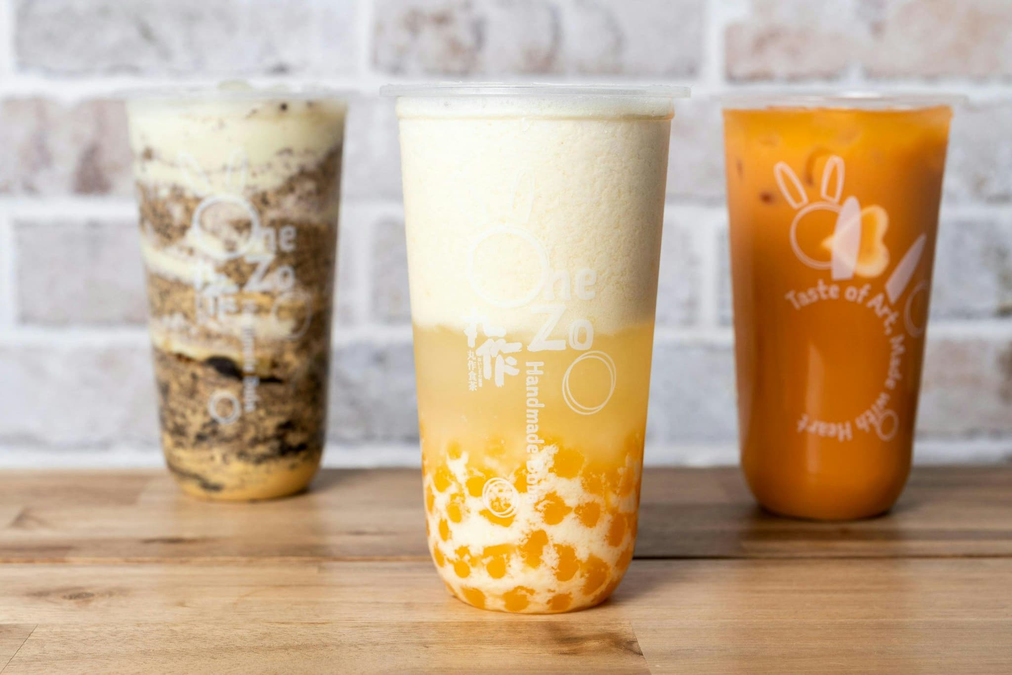 Three cups of bubble tea on a wooden café table