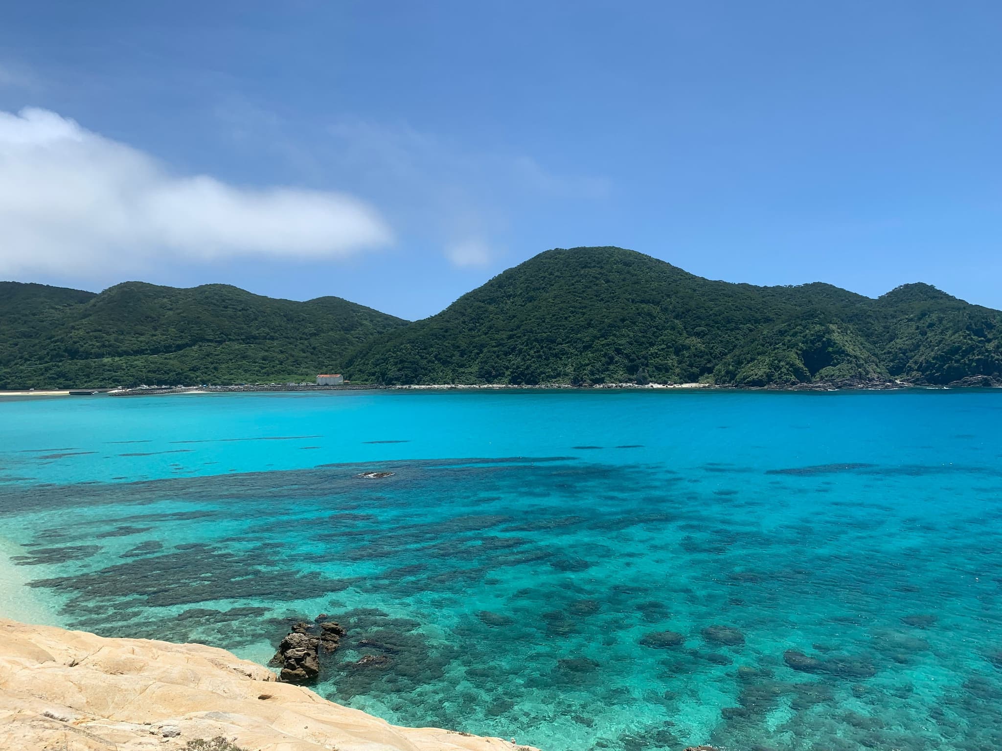 A turqoise sea on the beach and mountain in background on a clear day in Okinawa