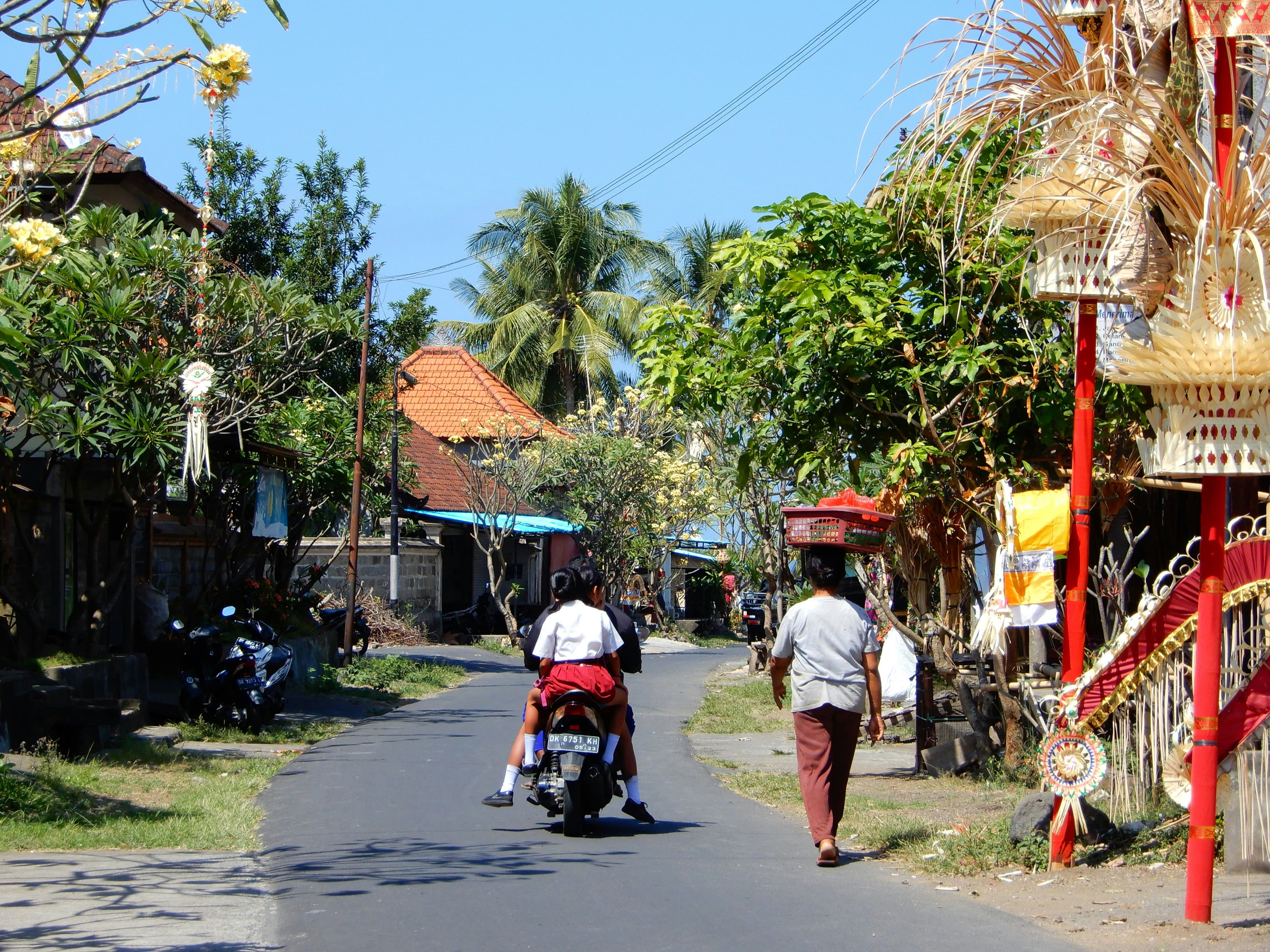 Scooter driving through an empty street in java with temple style buildings