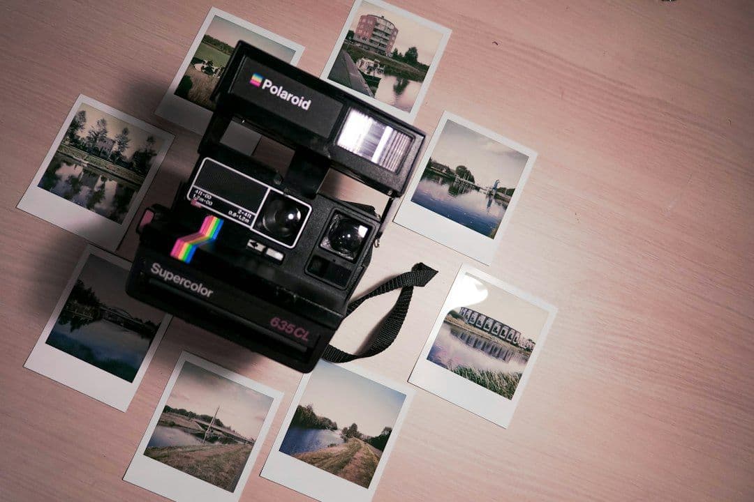 A Polaroid instant camera on a table surrounded by printed photos