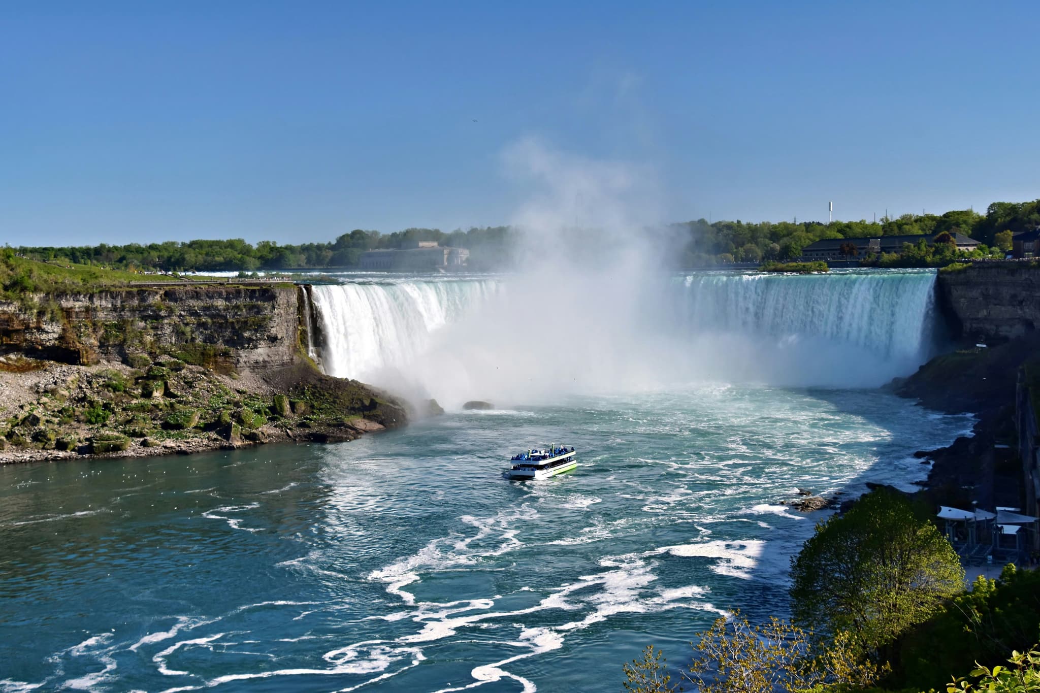 Boat entering the Niagara Falls, white water splashes can be seen