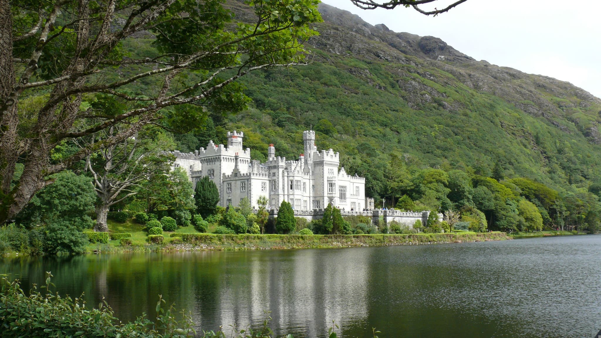 Kylemore Abbey reflected in still water surrounded by Connemara hills Ireland