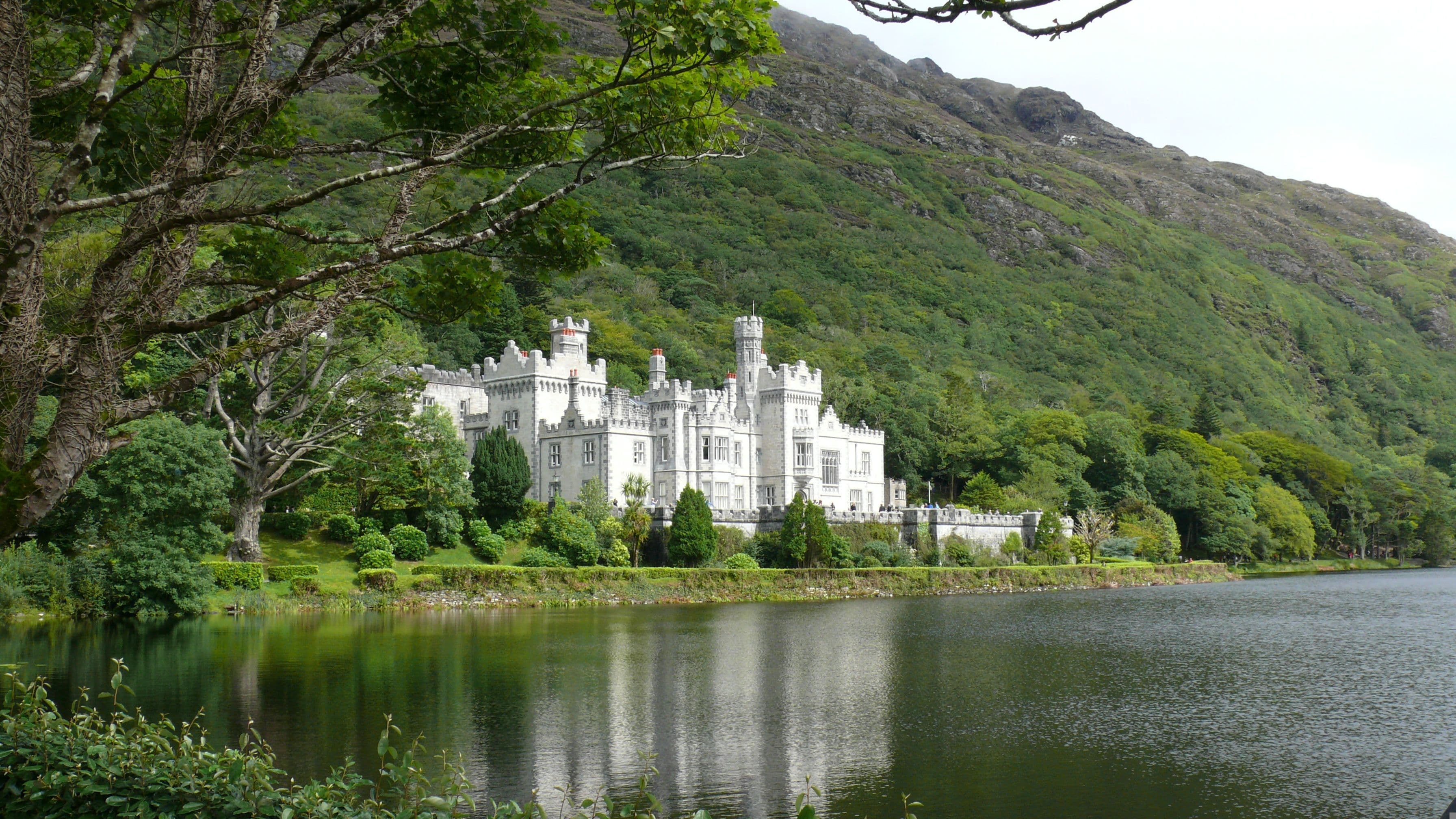 Kylemore Abbey reflected in still water surrounded by Connemara hills Ireland