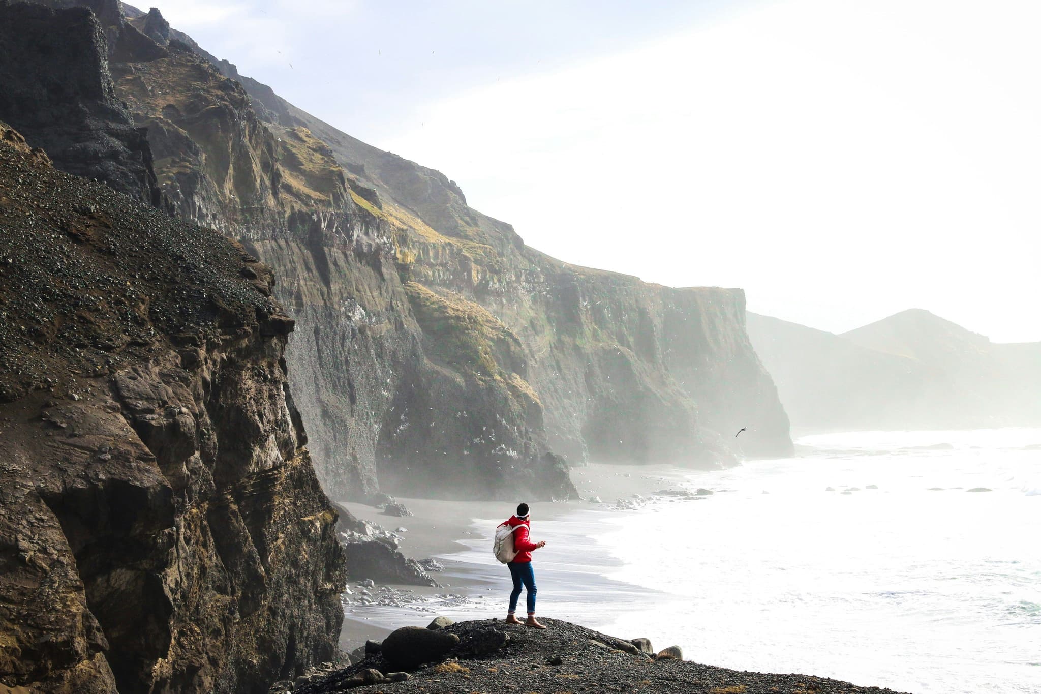Traveller standing on a rock near the cliffs and sea in Iceland