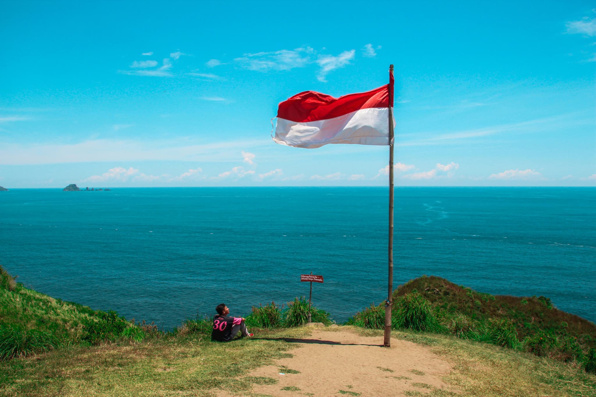 Big indonesian flag red and white on a hill overlooking the ocean and blue sky