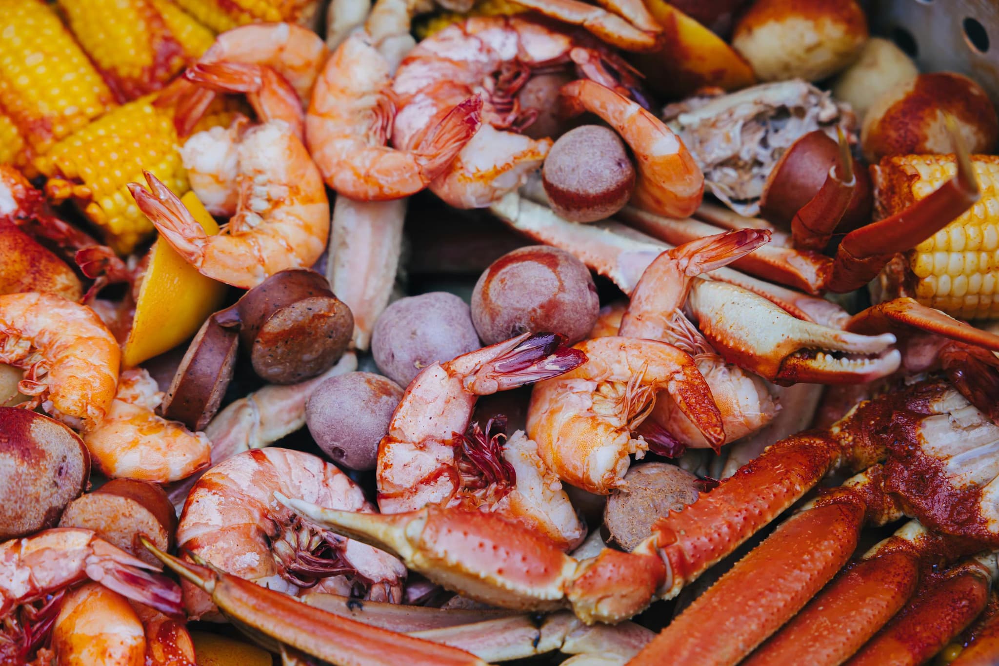 A vibrant seafood boil filled with seasoned shrimp, crab legs, sausage slices, corn on the cob, and red potatoes, conveying a festive and hearty meal.