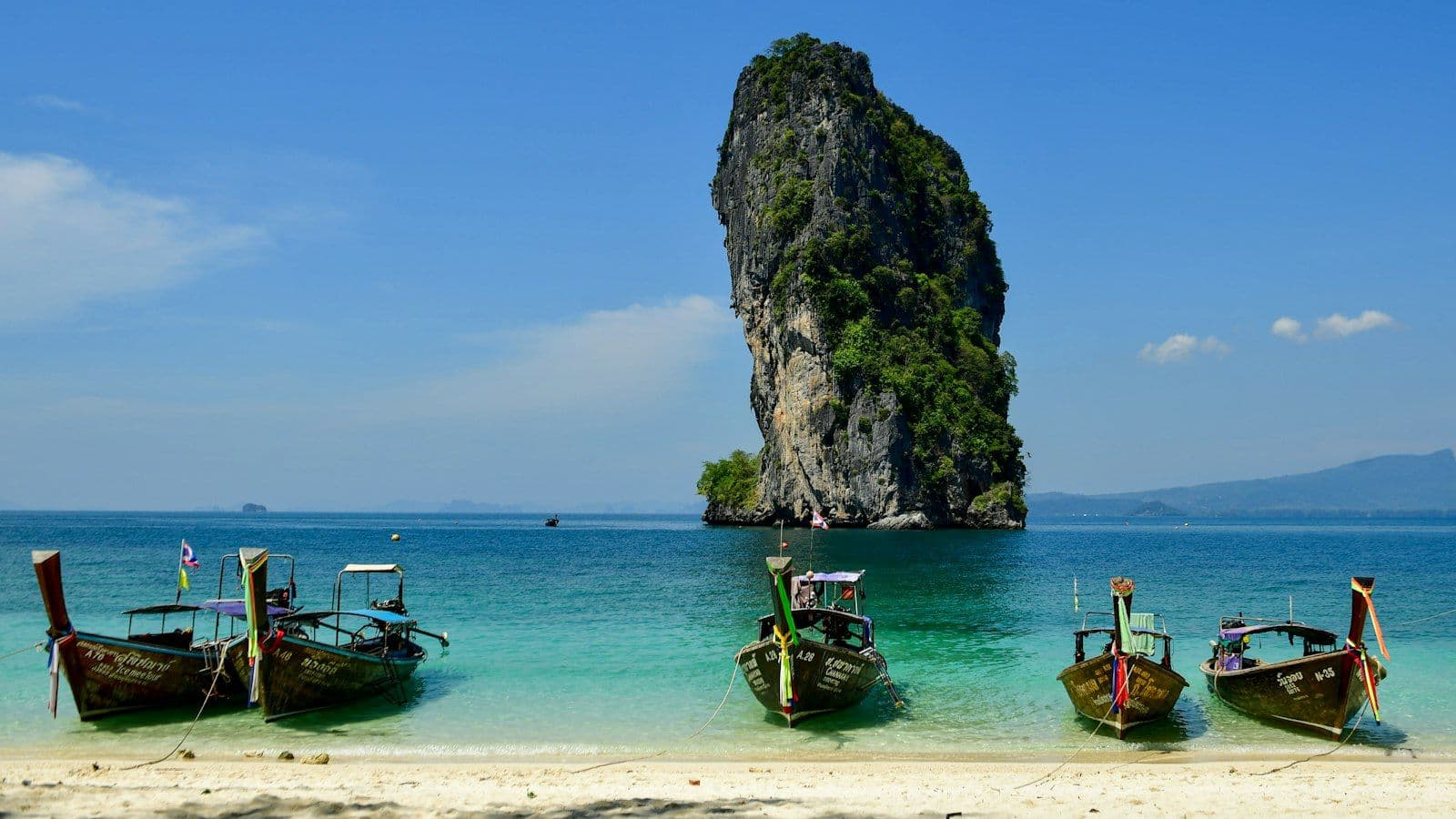 Traditional Thai long-tail boats on the crystal-blue waters around Poda Island, Thailand