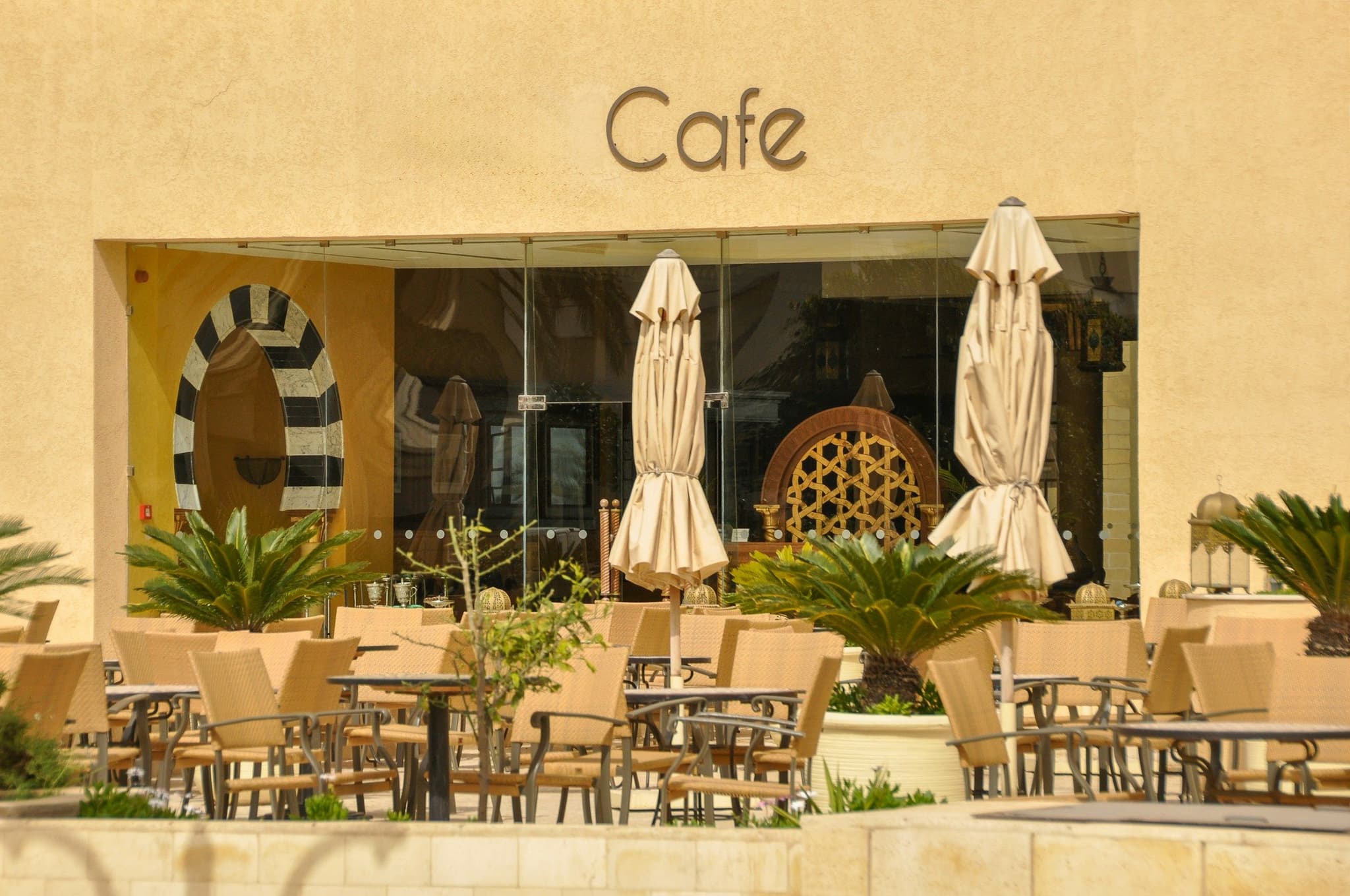An outdoor café terrace with woven chairs under a yellow facade in Tunisia