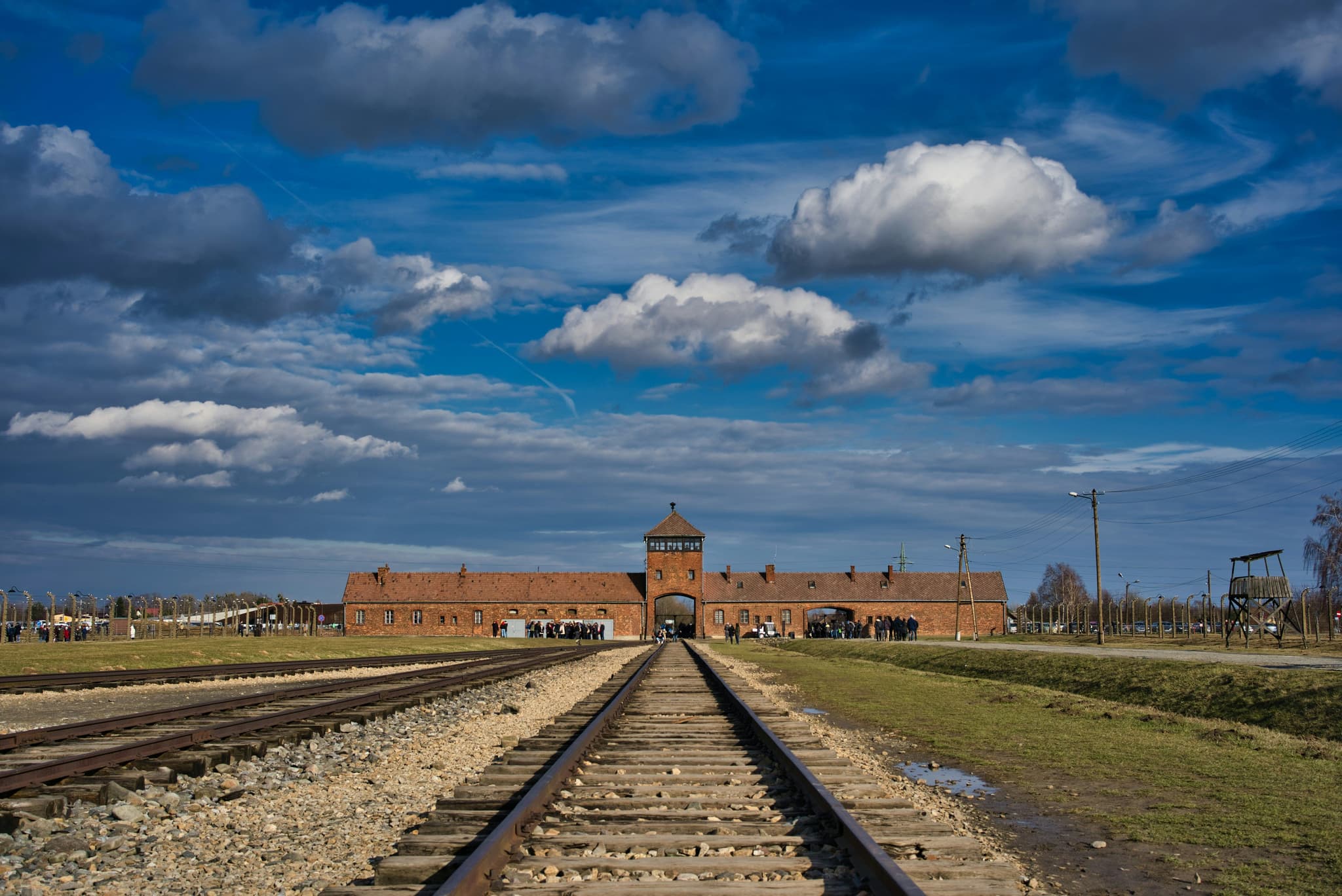 Train track leading to Auschwitz building on a cloudy day