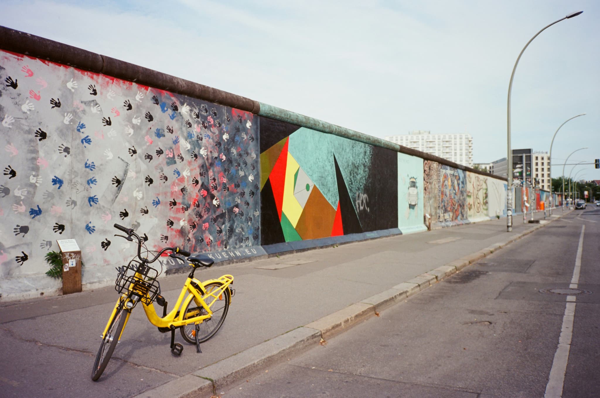 The berlin wall with colorful murals without people, there is a parked bicycle