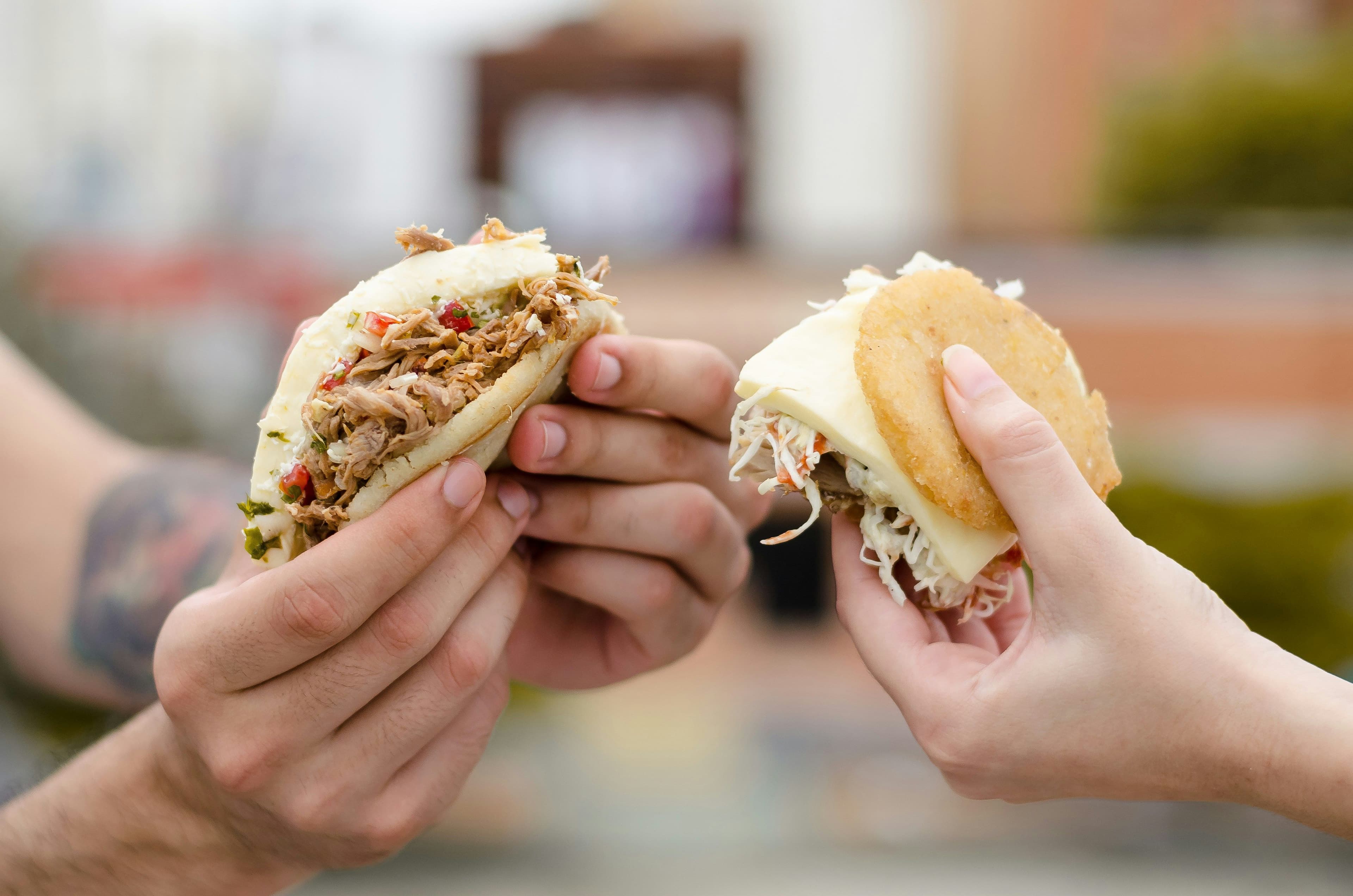 Hands holding arepas