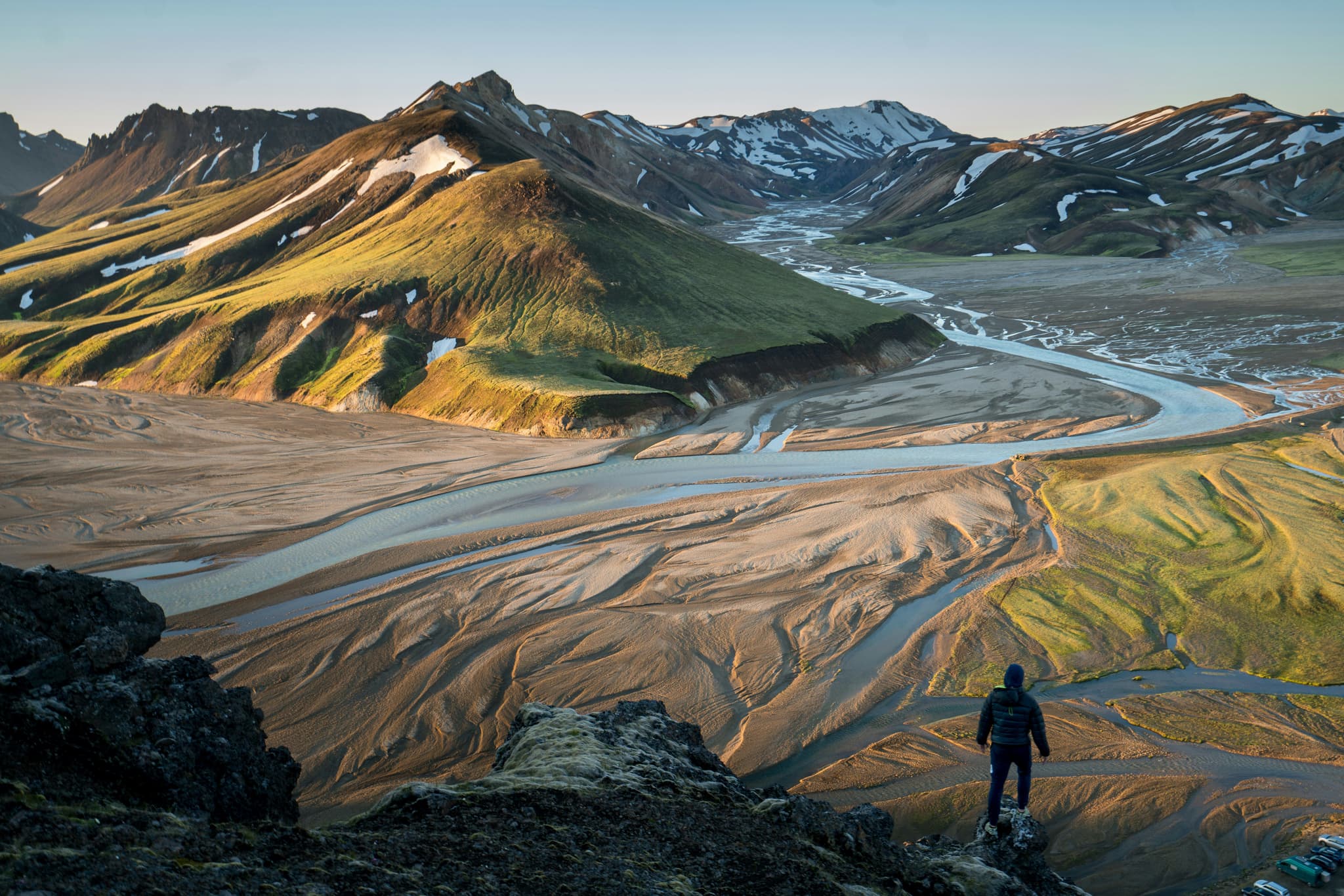 A traveller standing on a mountain looking at the valley and green mountains in Iceland
