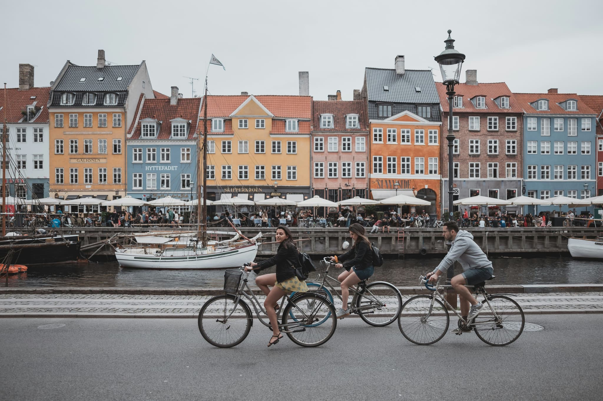 Three cyclists cycling next to the river and colorful houses in Denmark