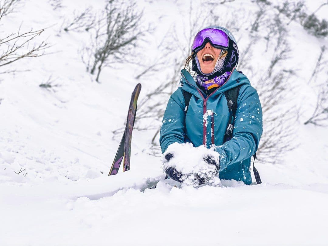 A skier holding her skis in the snow at Niseko, Japan.
