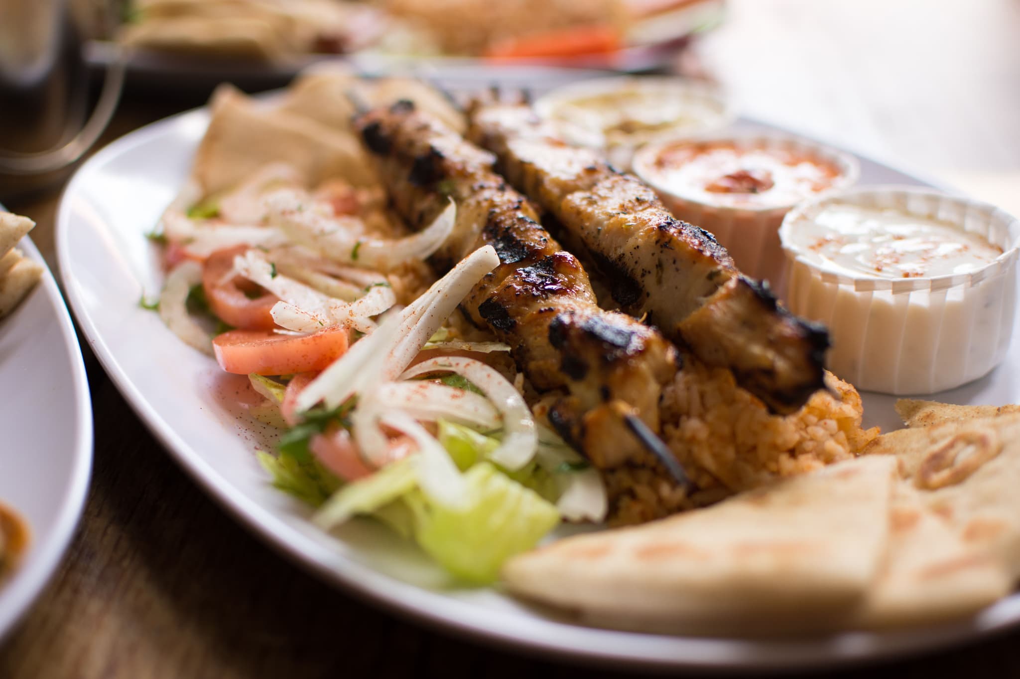 Souvlaki on a plate served with vegetables and two sauces