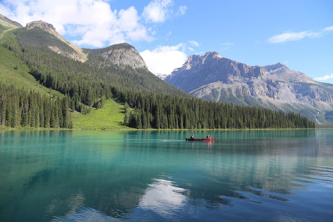 Bright blue lake in Banff National Park with mountains and forested hills in the background on a clear day.