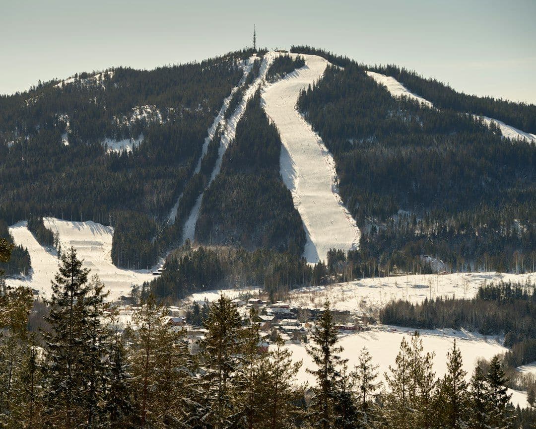 A small Norwegian ski slope and lift above a village, skiers on the snow.