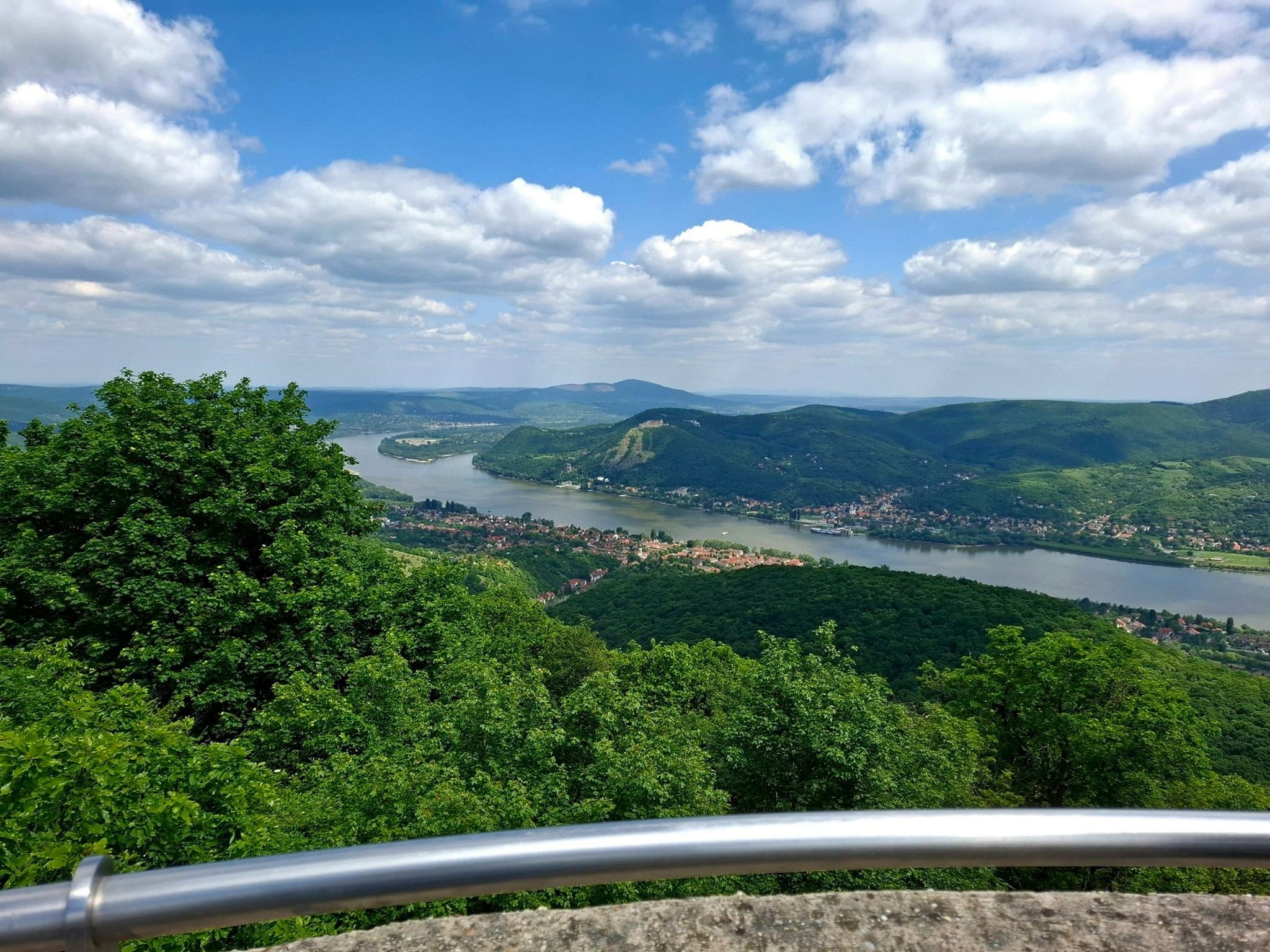 A wide view over the Danube, wooded hills and a riverside town from a lookout tower