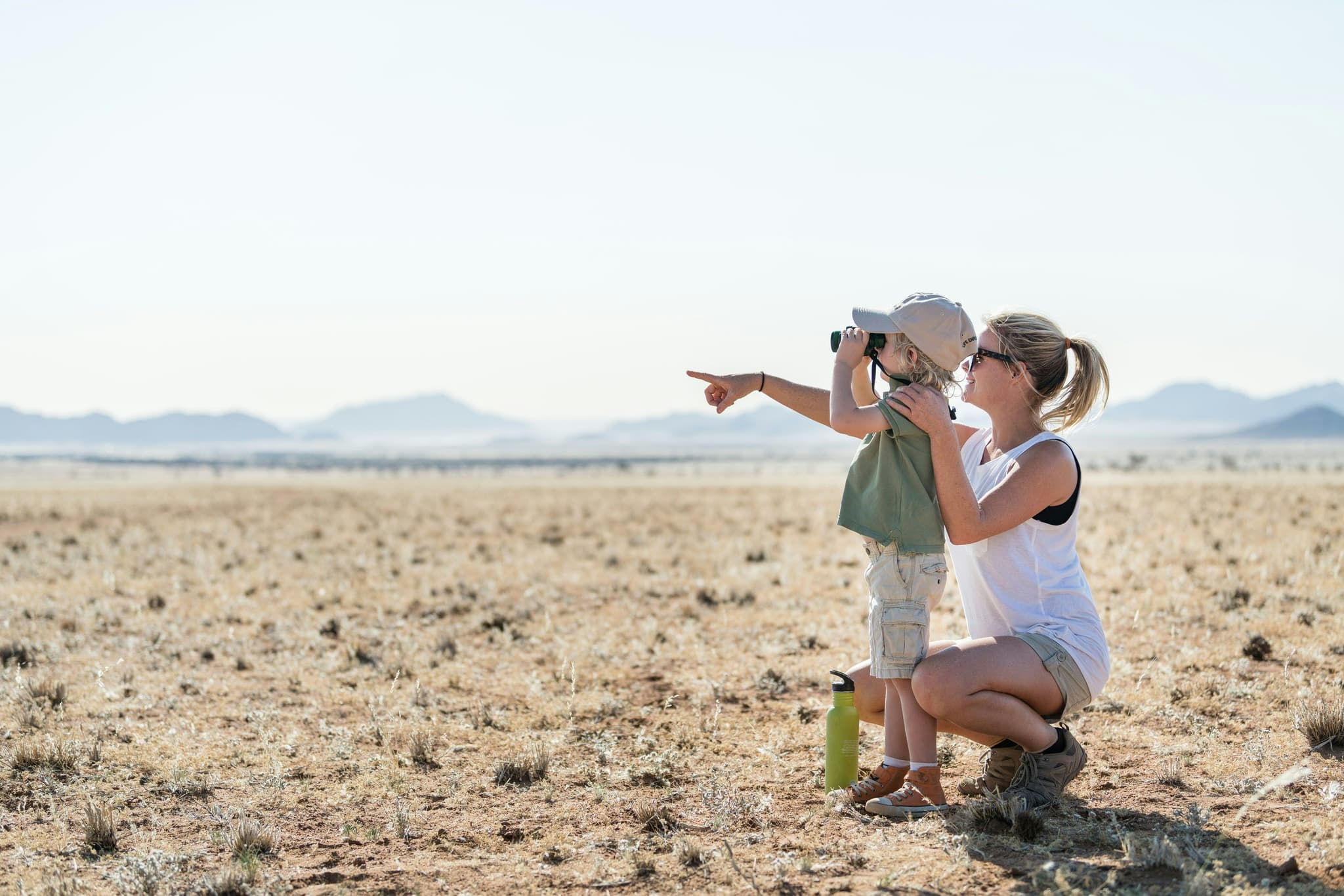 A woman holding her son in the desert looking at something