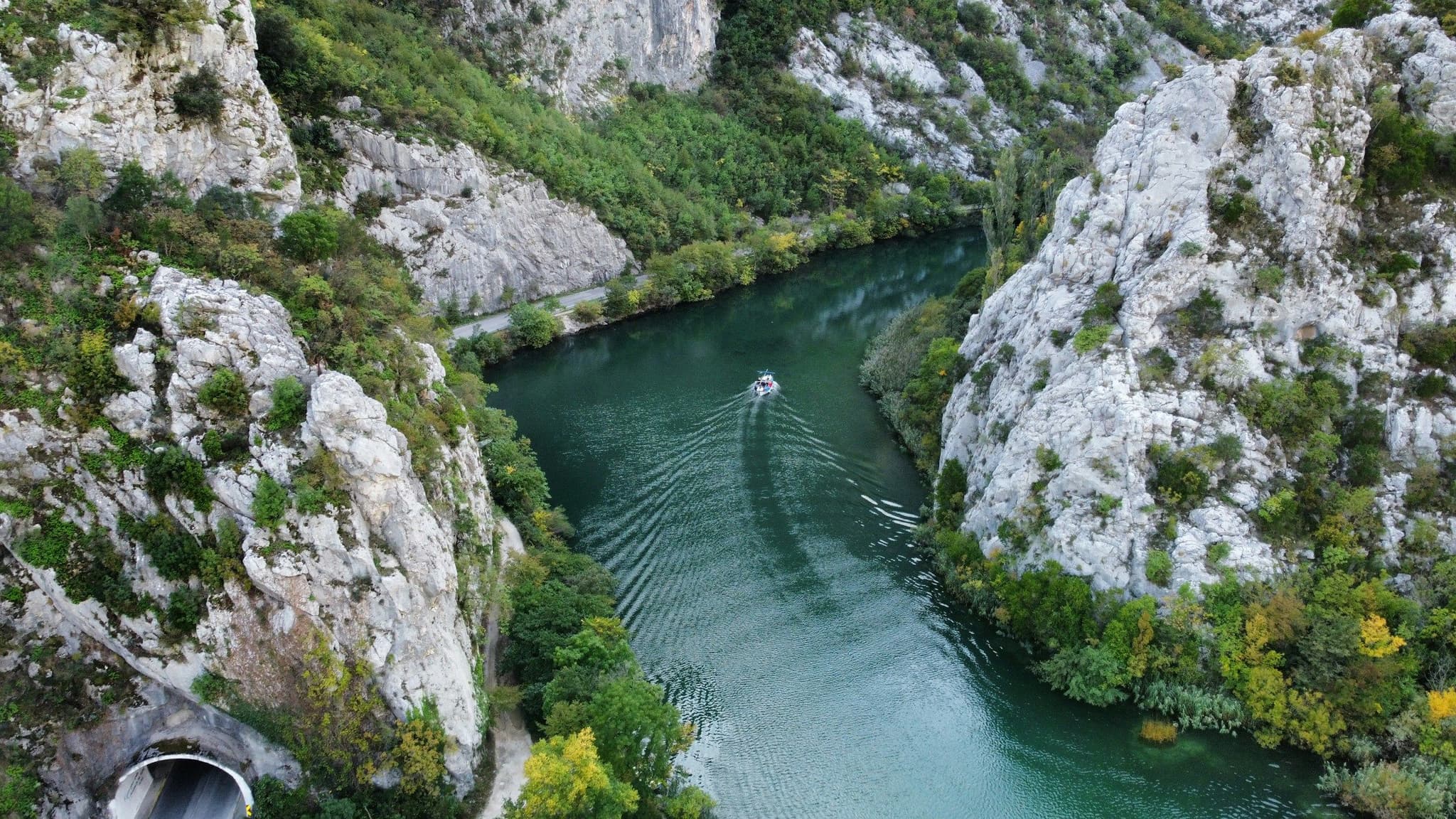 A small boat on the Cetina river between large boulders and green cliffs