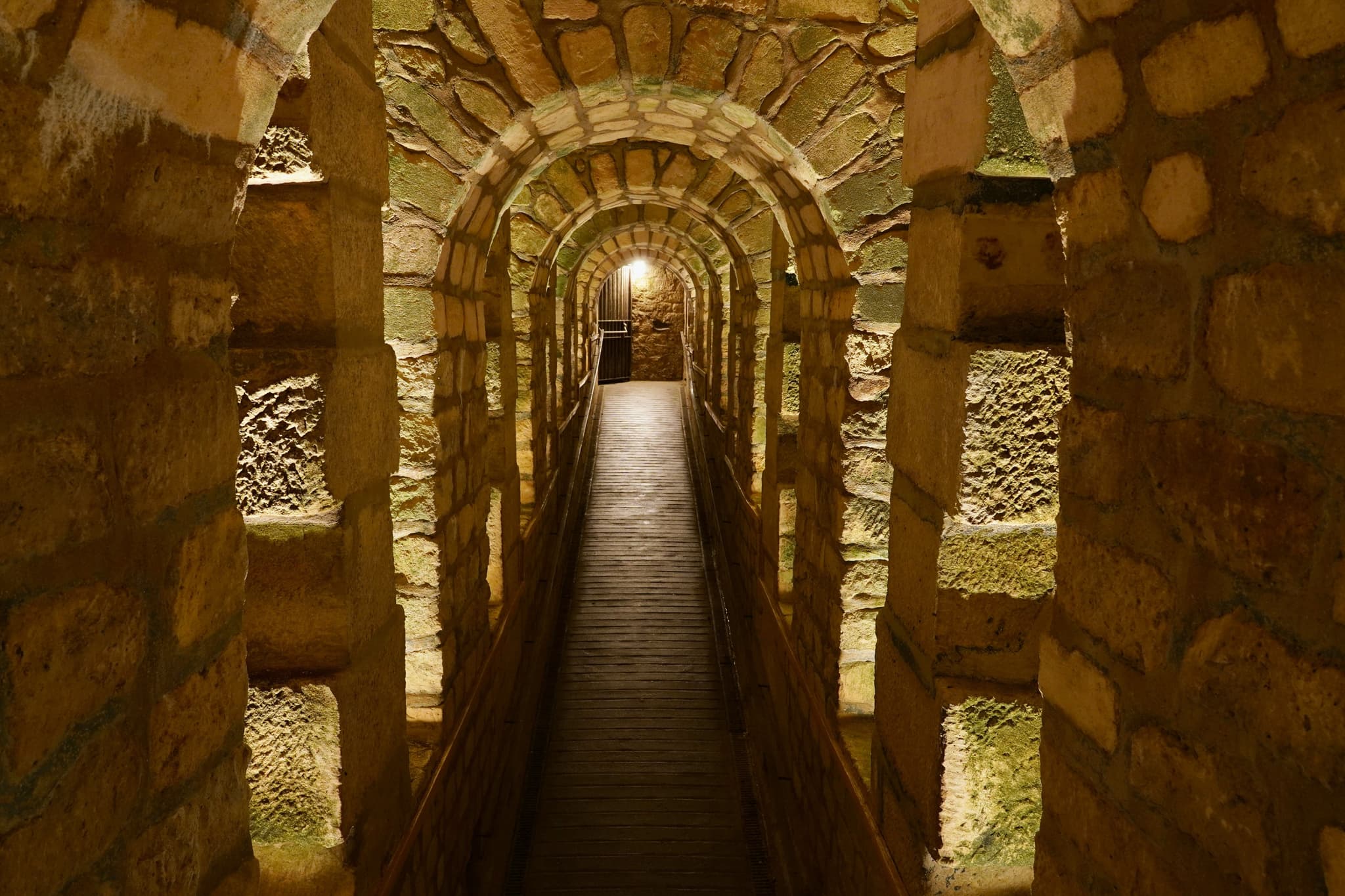 Lit stone tunnel arches of the Paris Catacombs