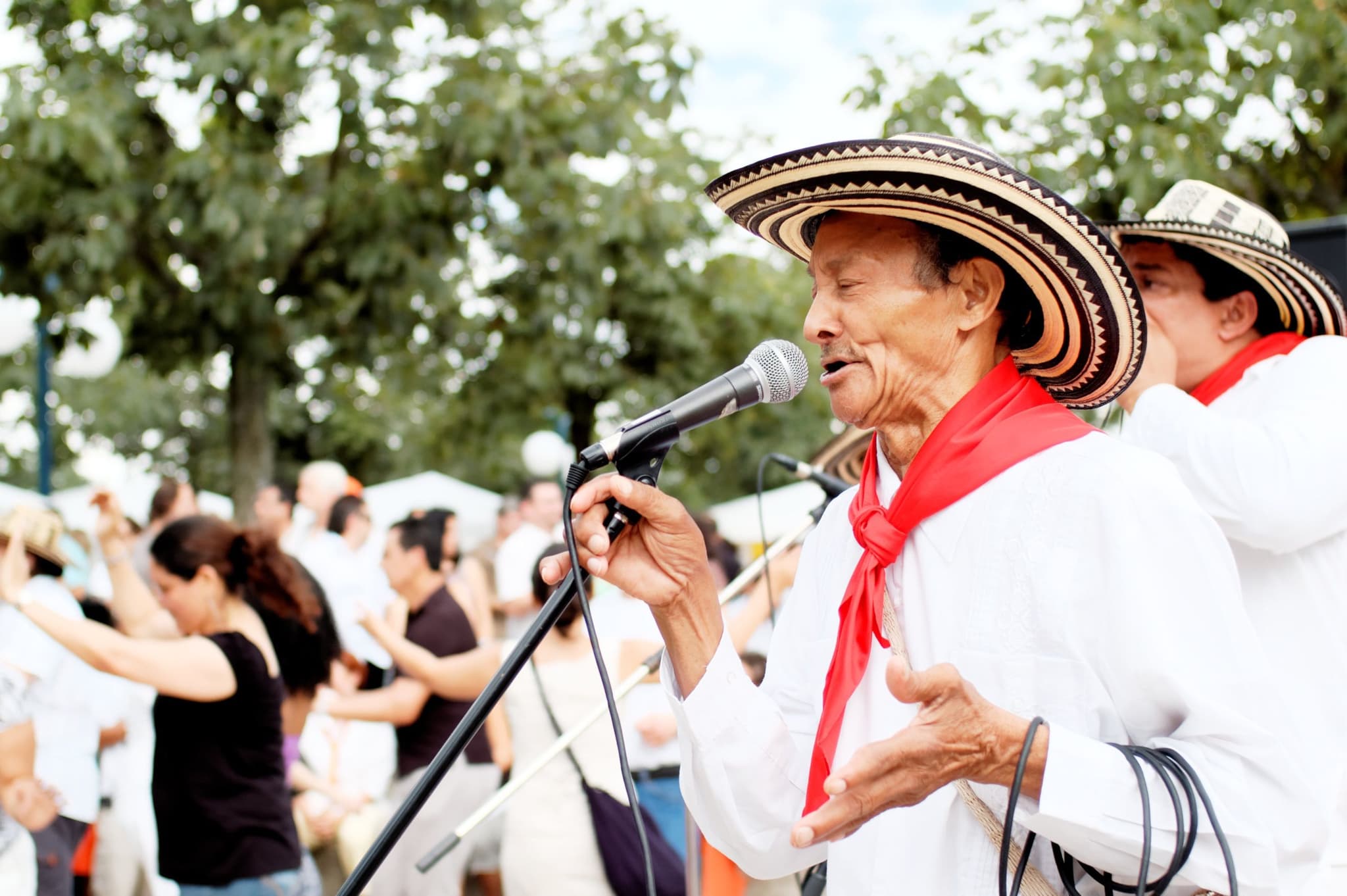 Local man singing wearing a sombrero, dancing people in the background