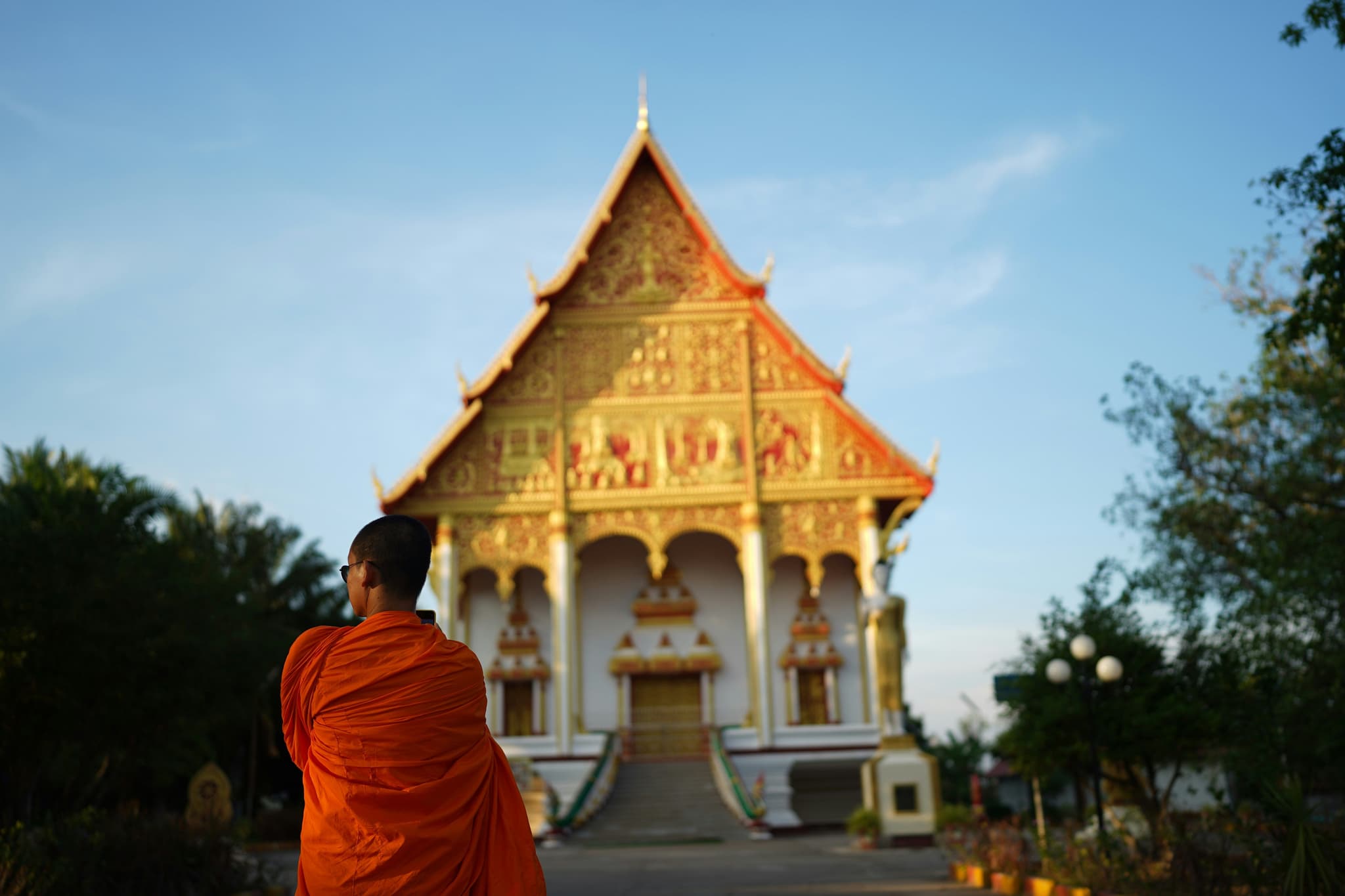 Monk standing in front of golden temple in Laos