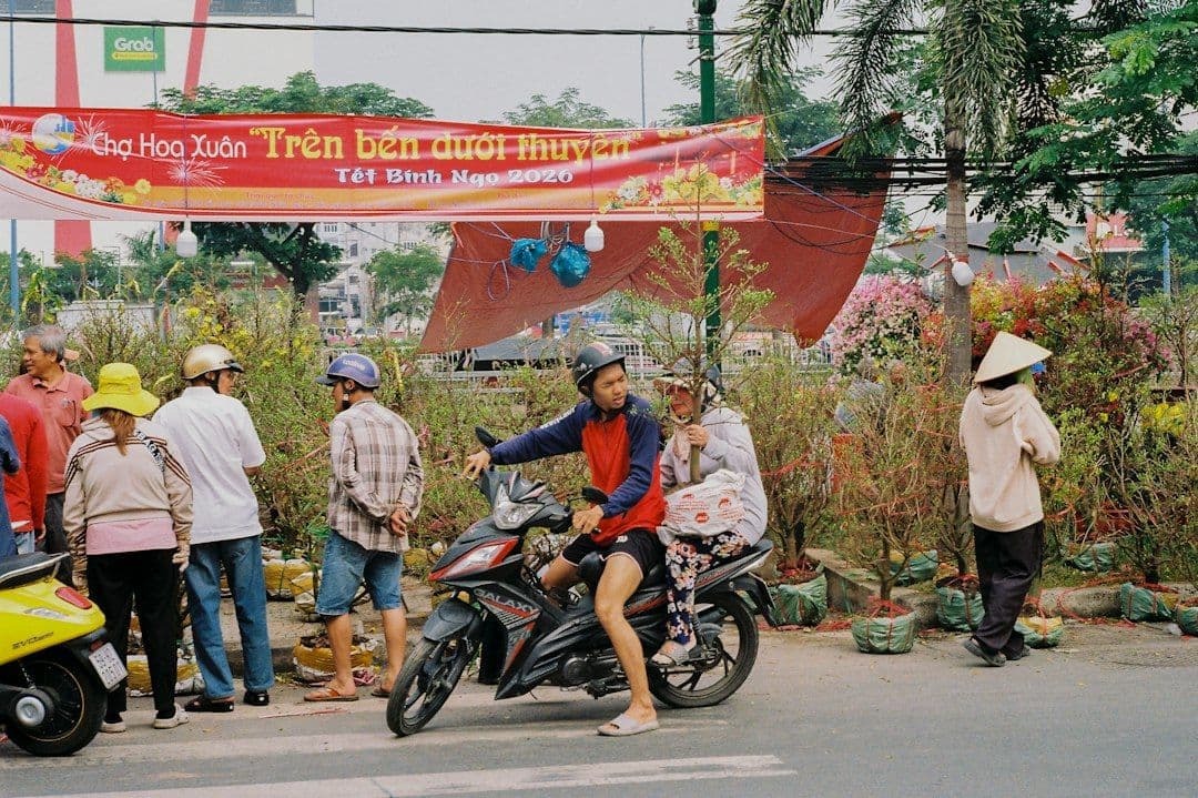 Locals carrying flowers through an outdoor market stall ahead of Tet