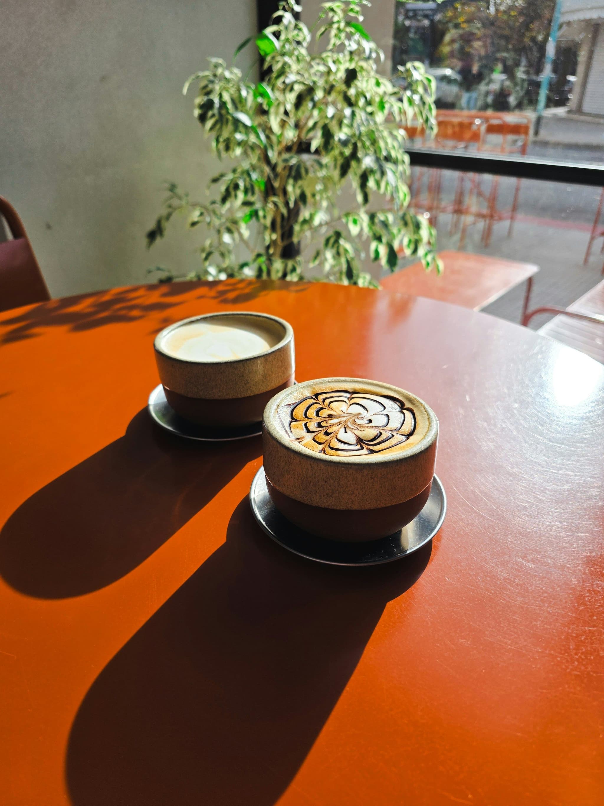 Two coffees on a sunny café table