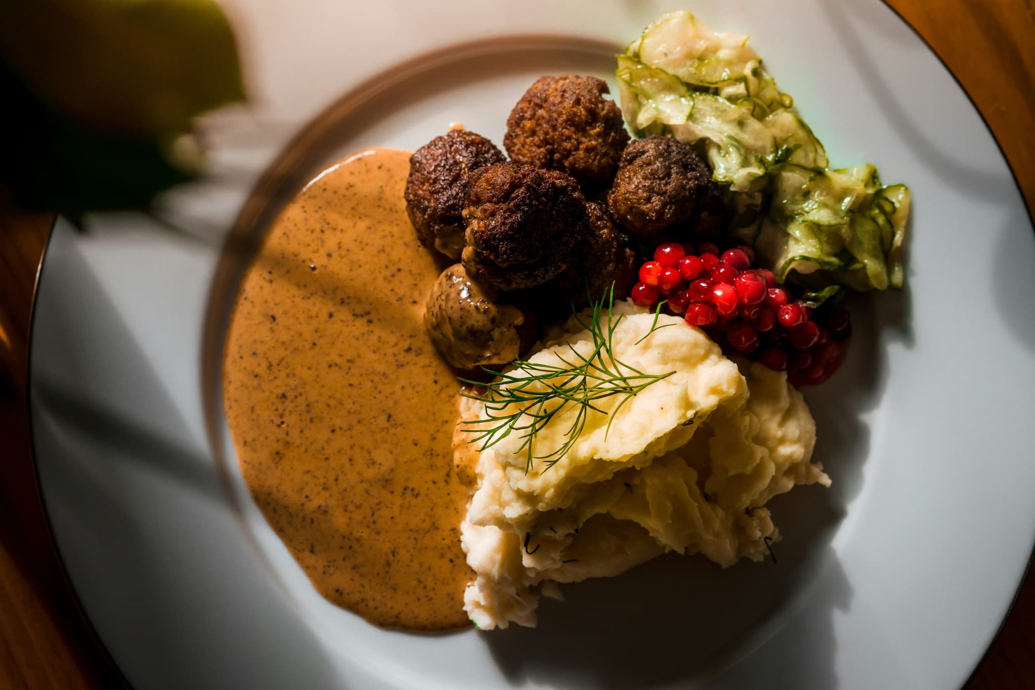 A plate of Swedish meatballs with lingonberry sauce and mashed potatoes
