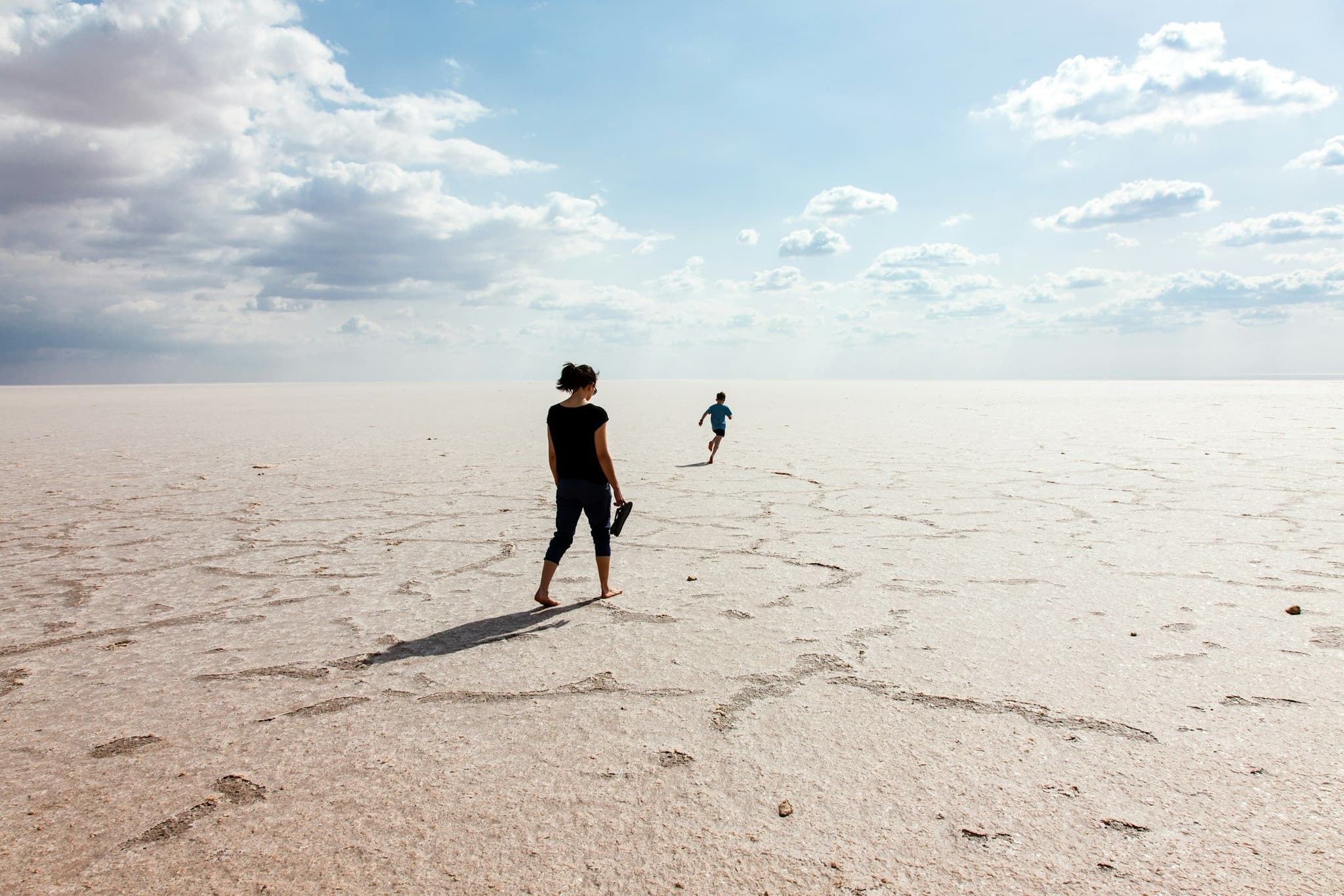 Two people walking across the wet salt flat of Chott el Djerid