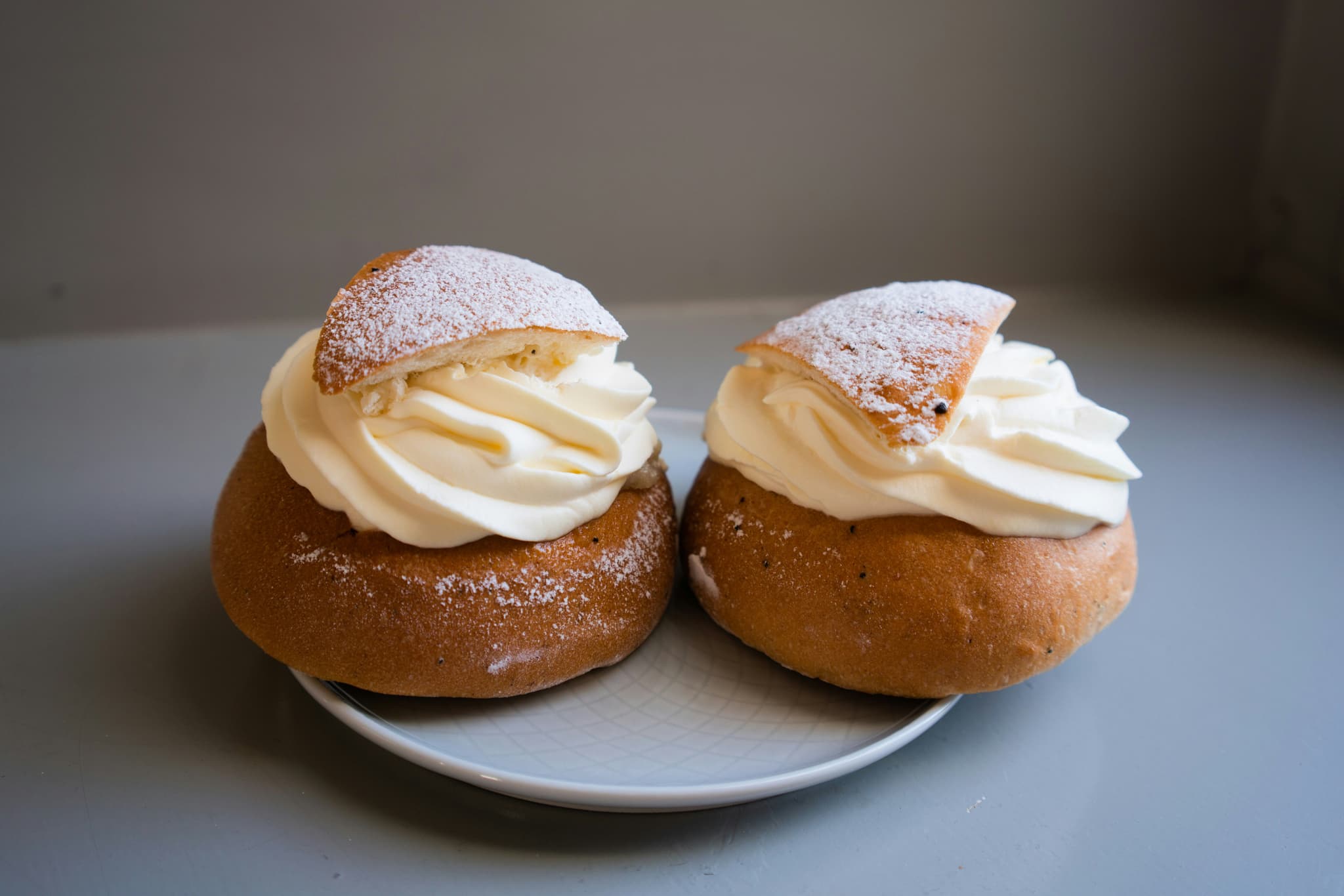 Two cream-filled semla buns dusted with icing sugar