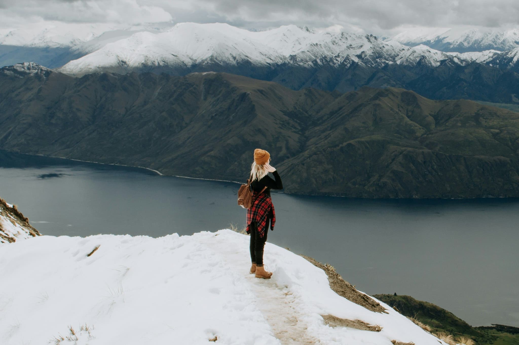 Solo traveller standing on a mountain cliff covered in snow