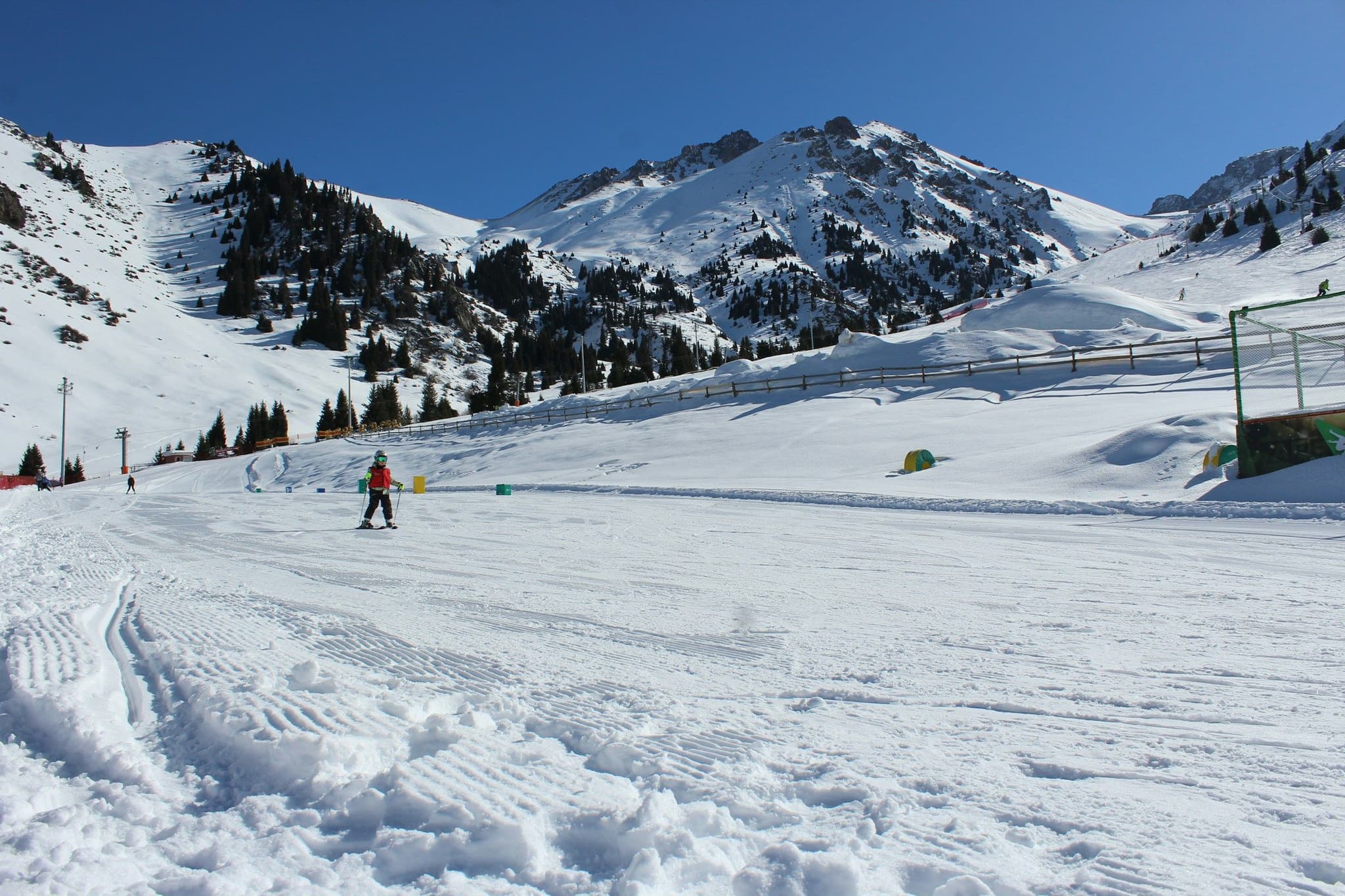A young skier on the nursery slope at Shymbulak with mountains behind