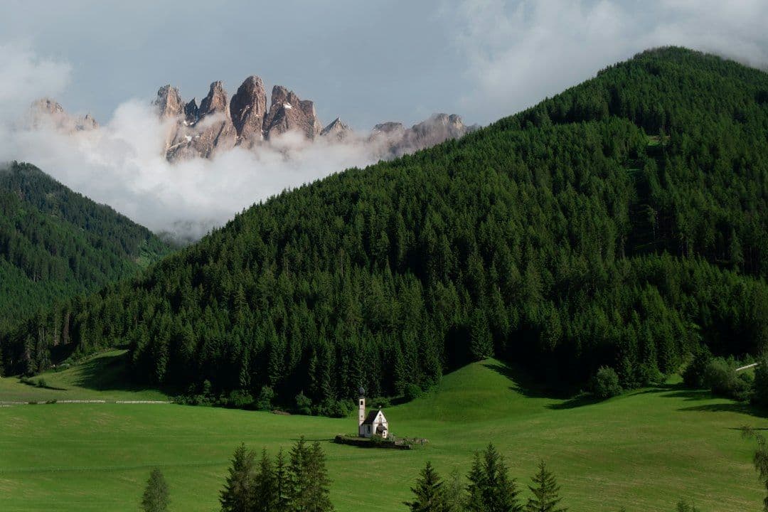 A small church with the Dolomites' Odle Mountains rising behind it
