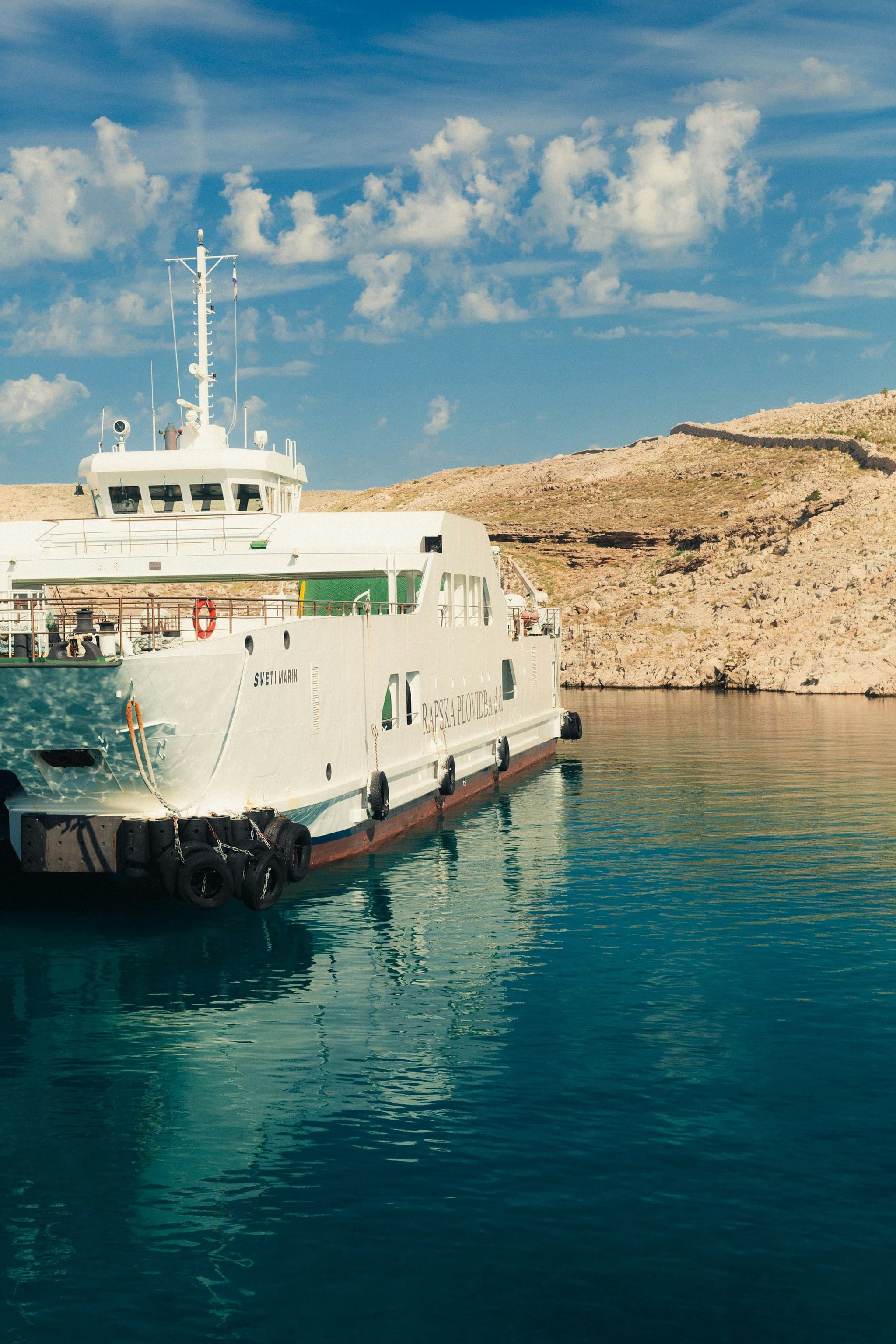 A white car ferry at the dock on the island of Rab