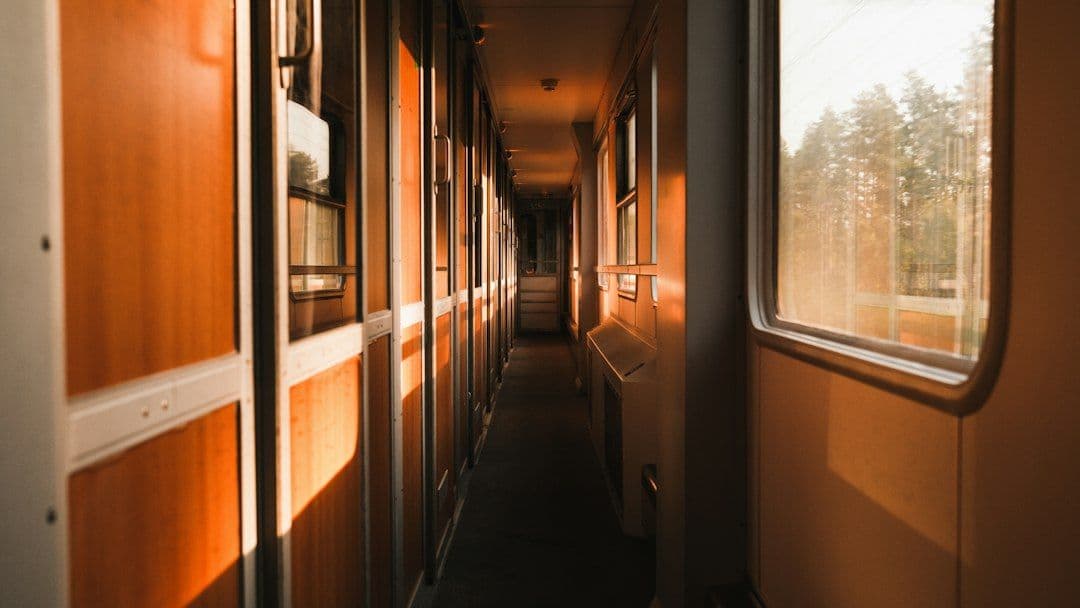 A narrow sleeper-car corridor on a European night train, leading toward a window.
