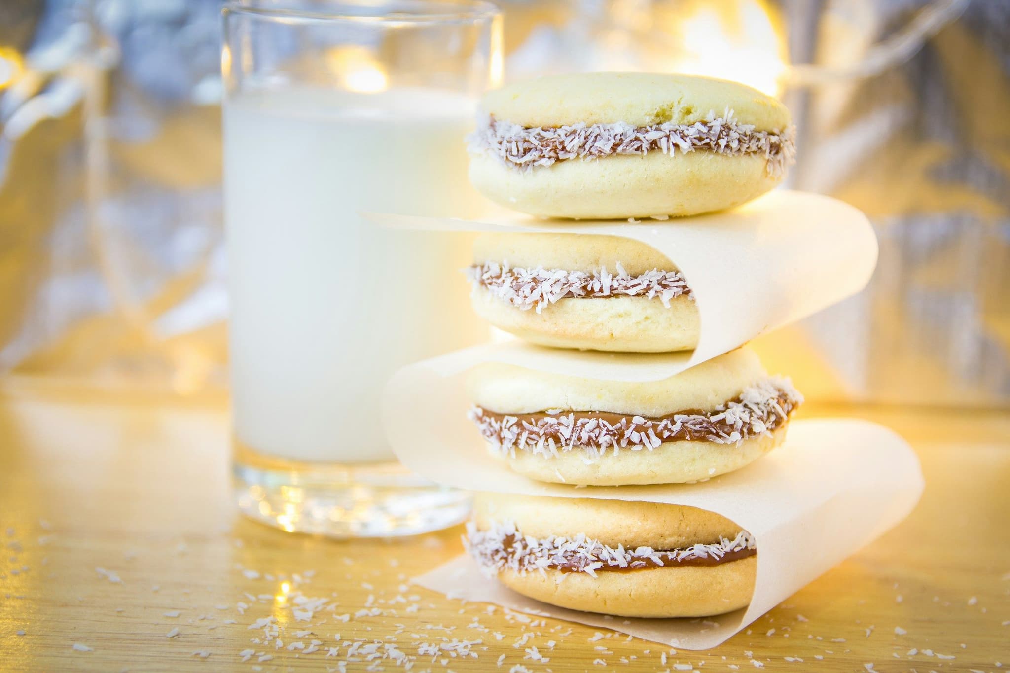 Alfajores filled with dulce de leche beside a glass of milk