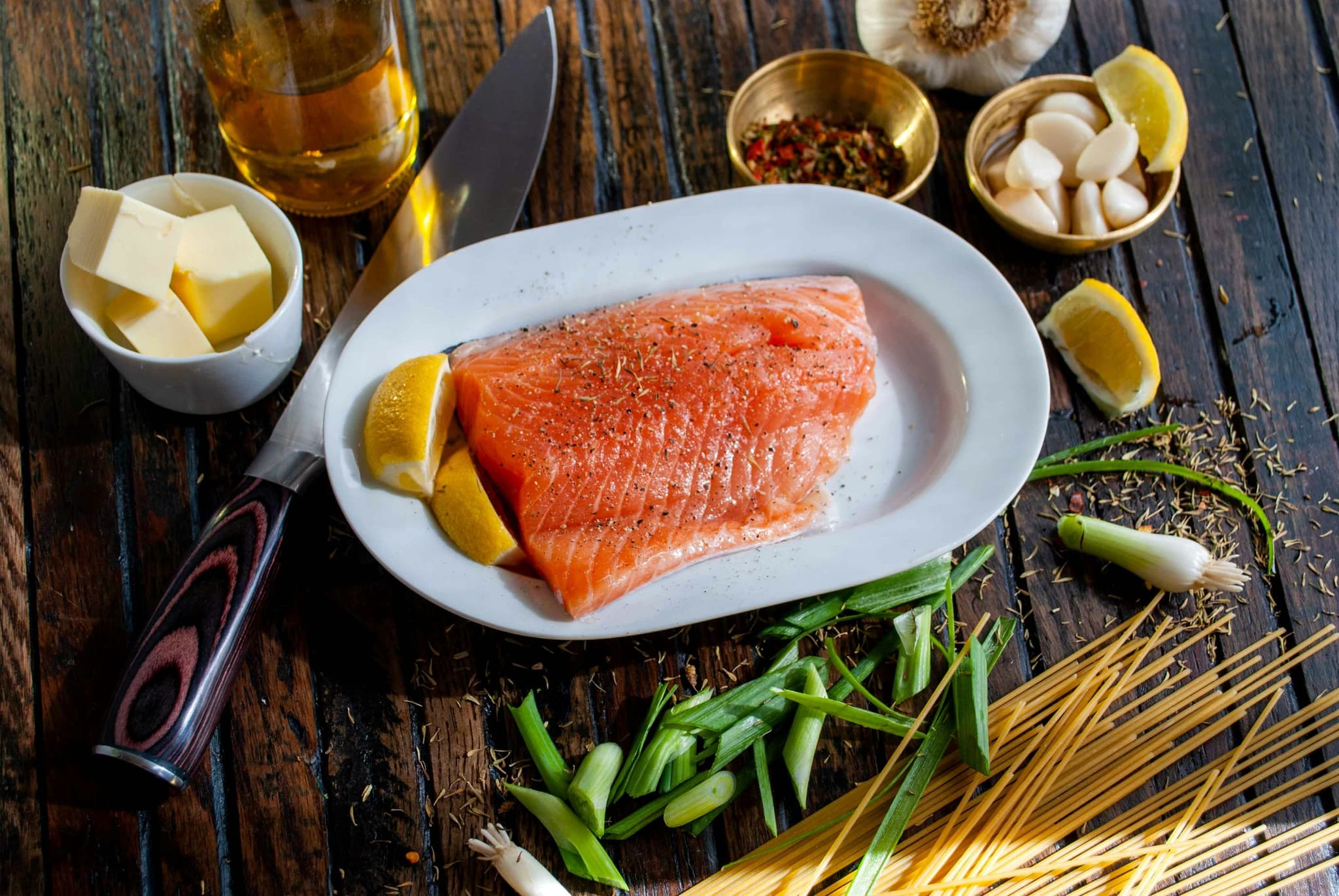 Salmon on a white plate with lemons and butter on the side