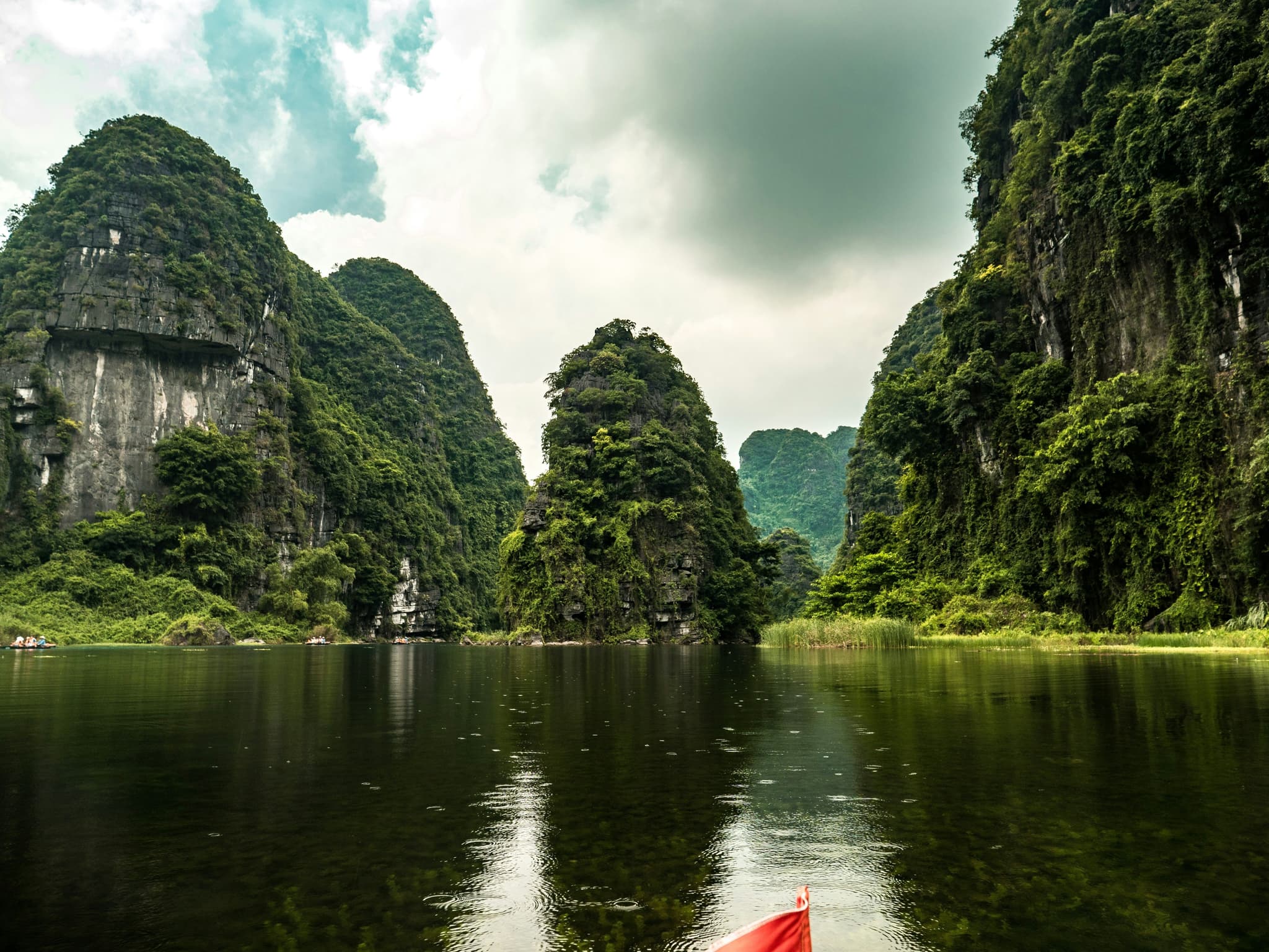 Lake with green limestone cliffs during rainfall