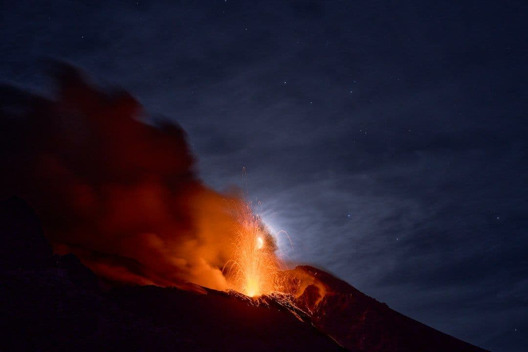 Stromboli volcano erupting with smoke and lava at night