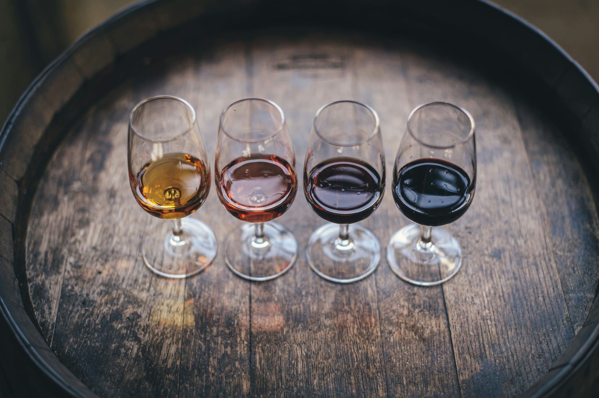 Four types of wine in 4 wine glasses on a barrel
