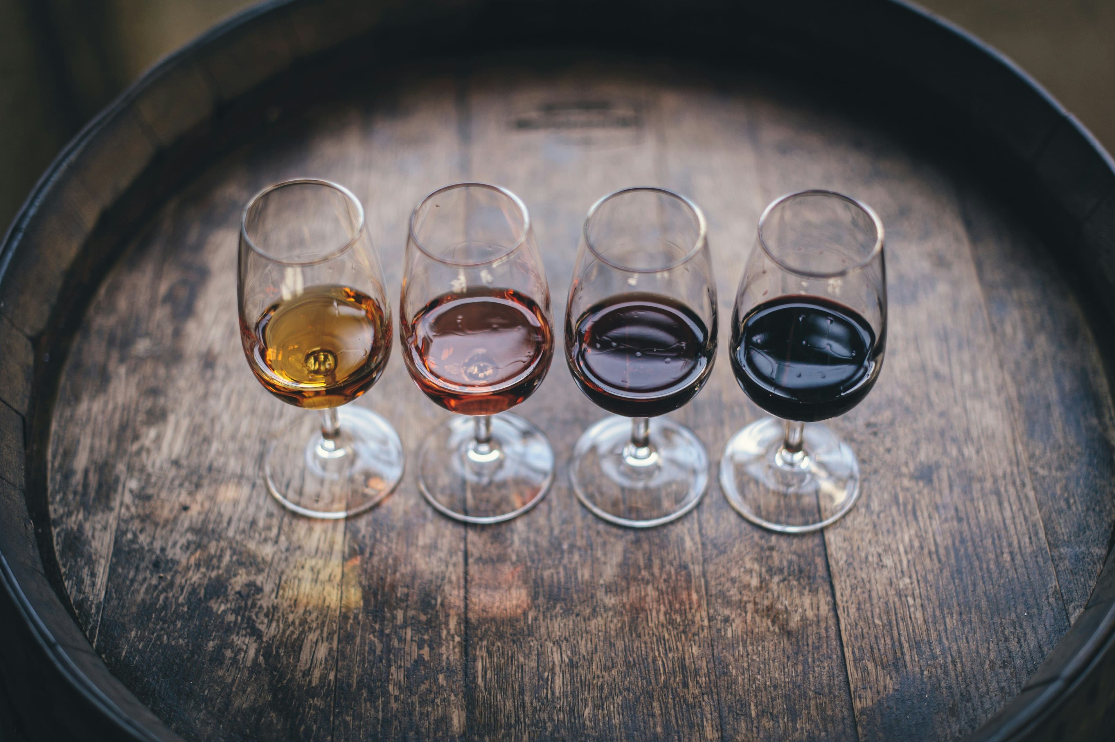 Four types of wine in 4 wine glasses on a barrel
