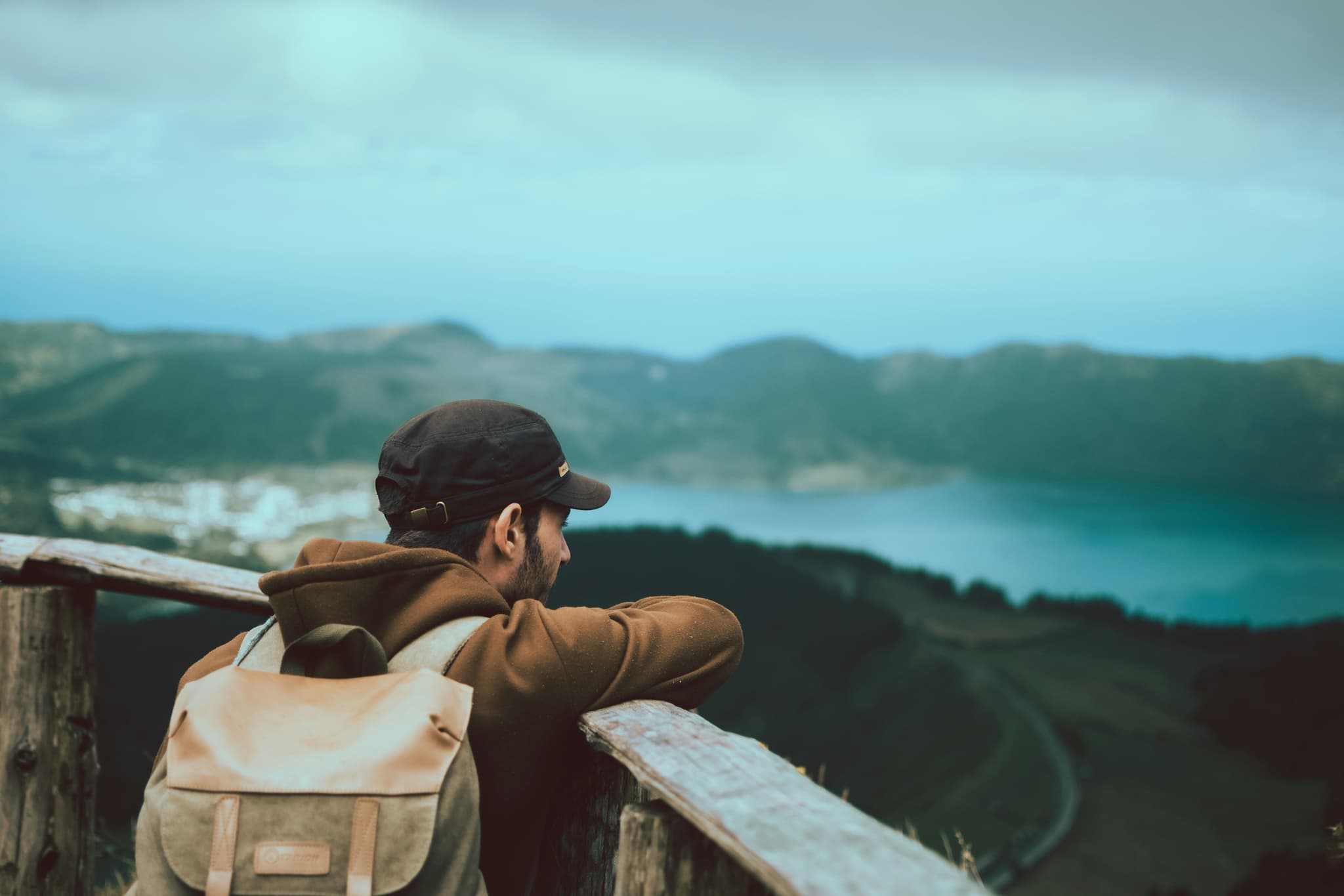Male solo traveller with backpack looking at the view of mountains and lakes