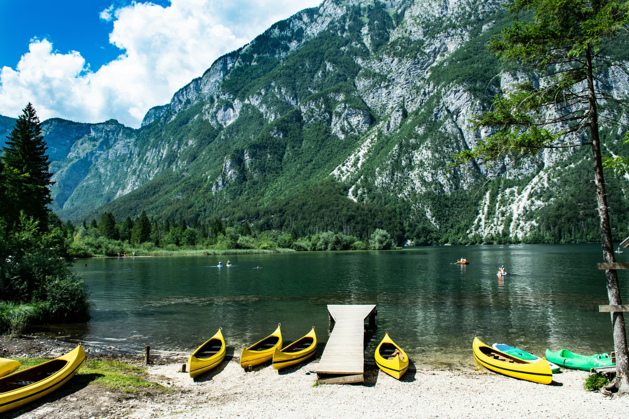 Kayaks prepared for lake trip next to a lake surrounded by green nature in Lake Bohinj
