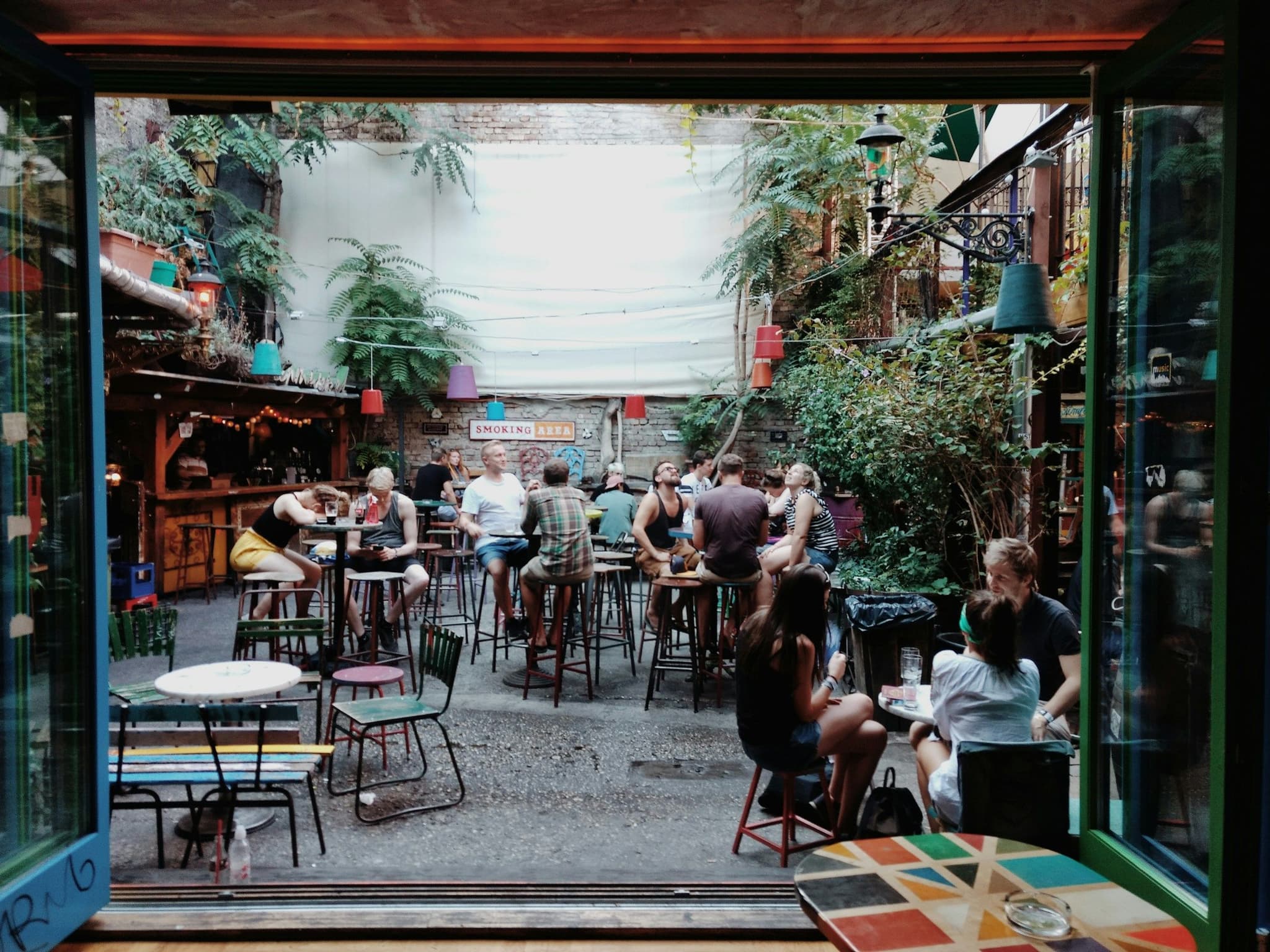 People at tables among quirky decor inside a Budapest ruin bar