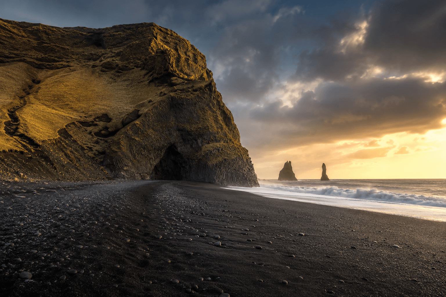 The mountain cliff of reynisfjall on the beach during sunset with clouds