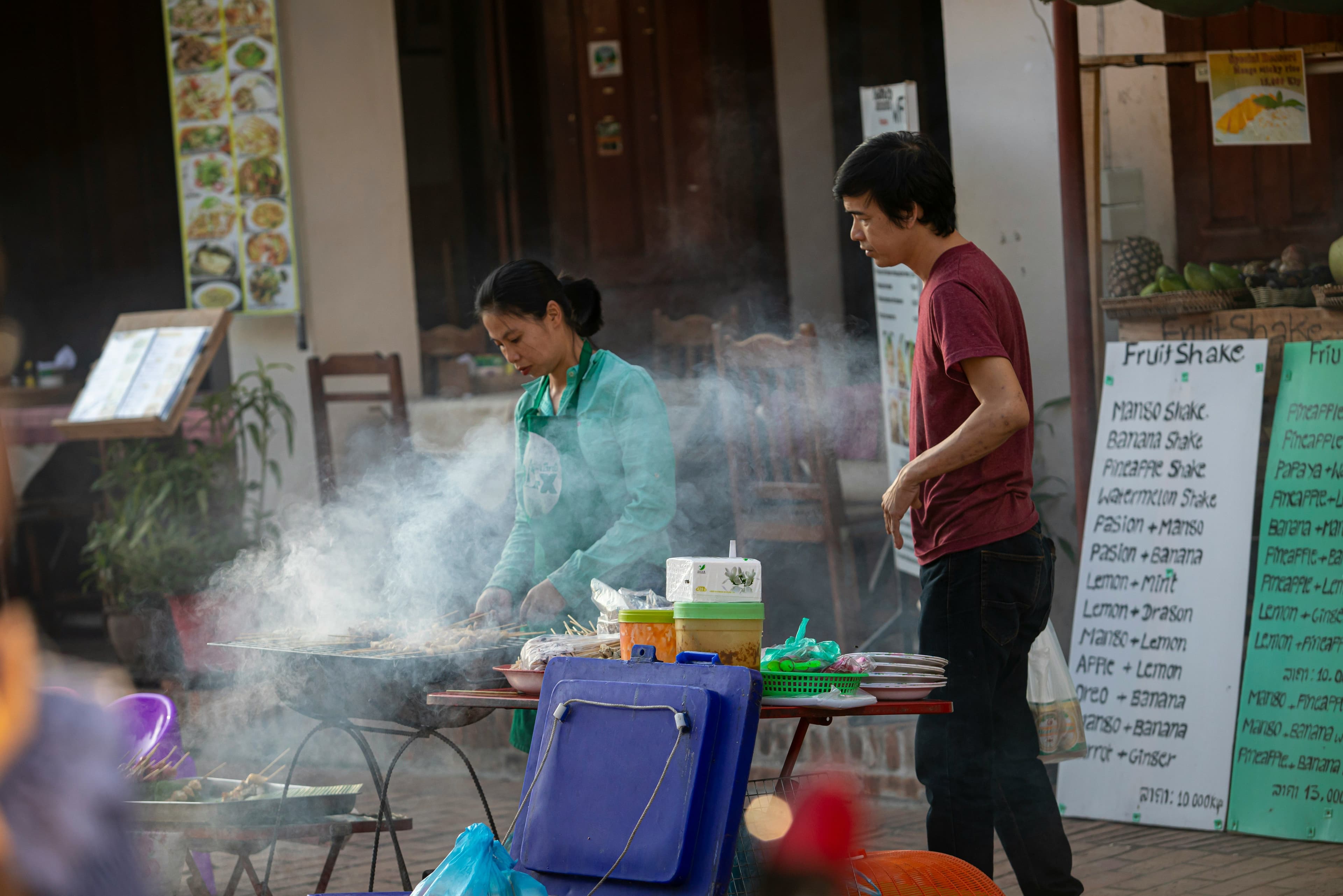 locals in laos making food in a street food stall