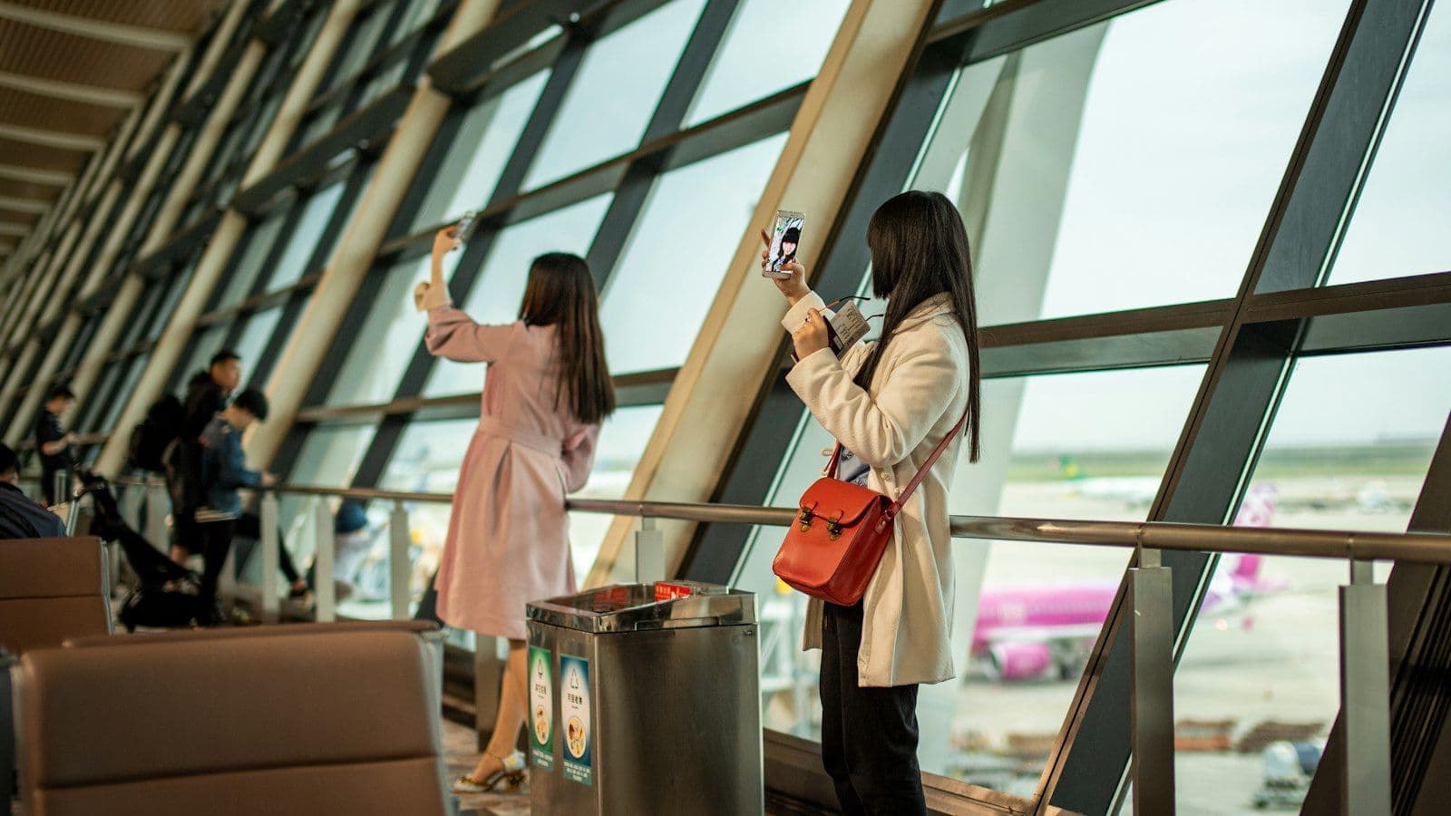 Two travelers with phones in hand at an airport terminal